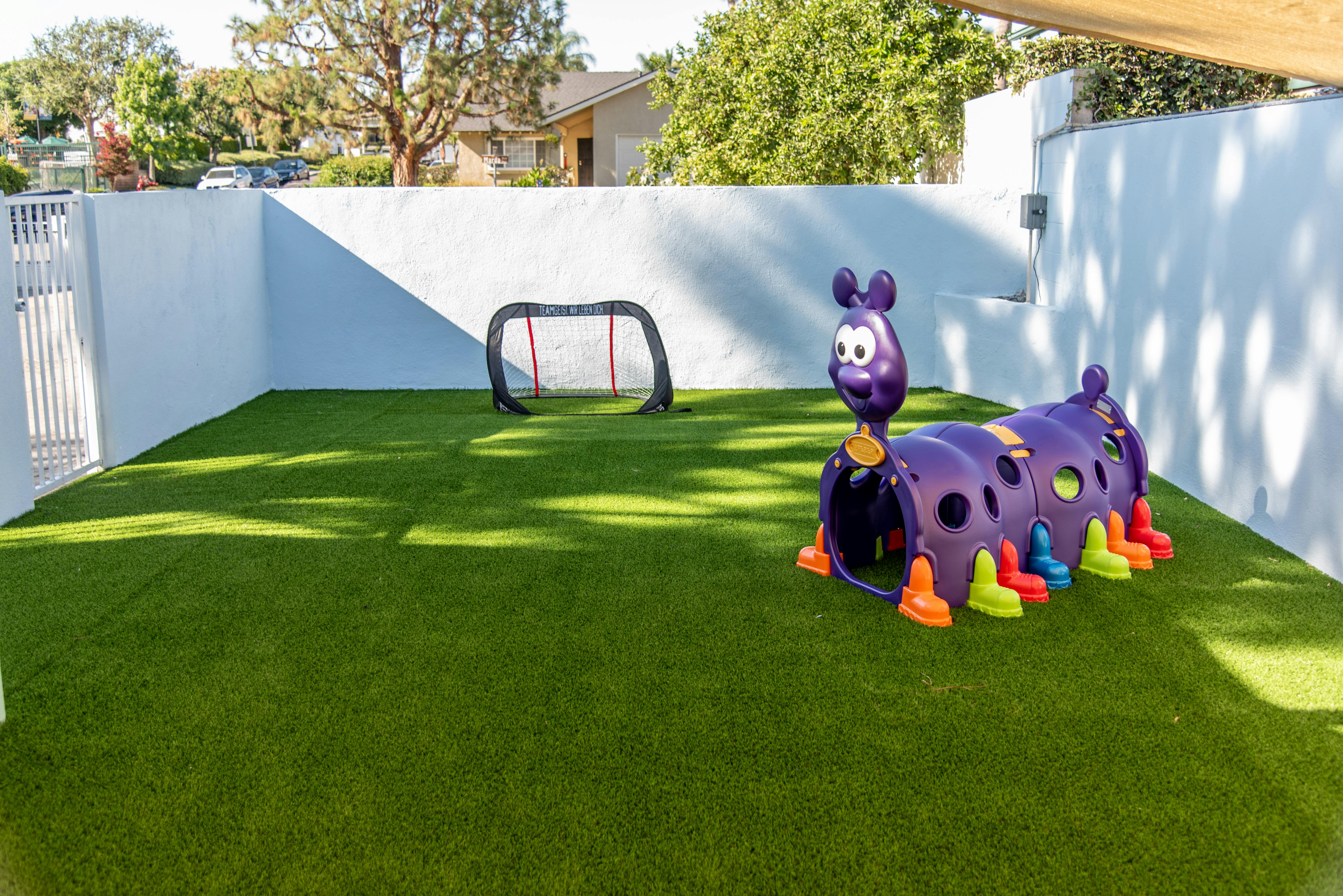 Playground with artificial turf, a purple caterpillar tunnel, and a small soccer goal