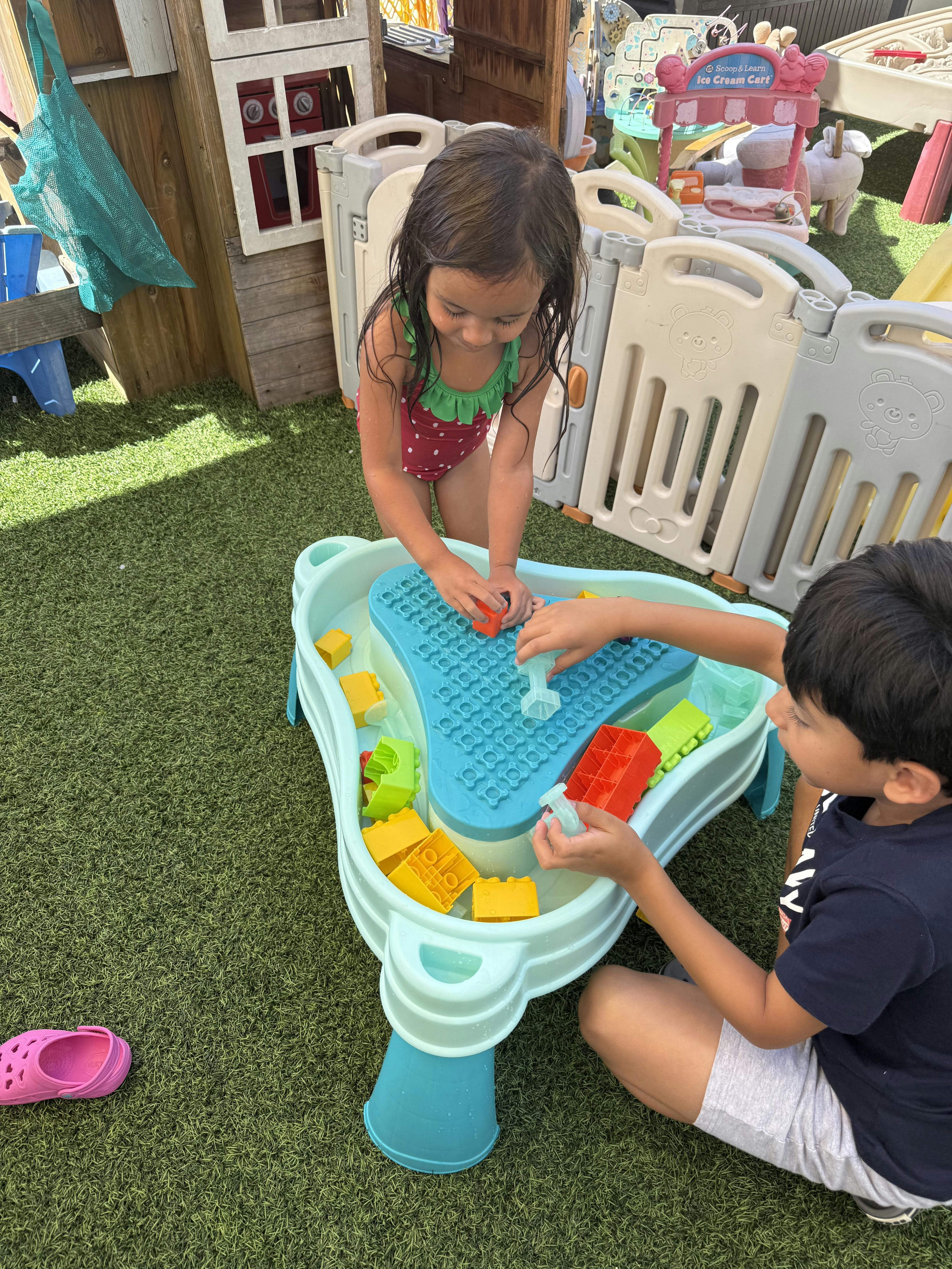 Two children playing with a water table