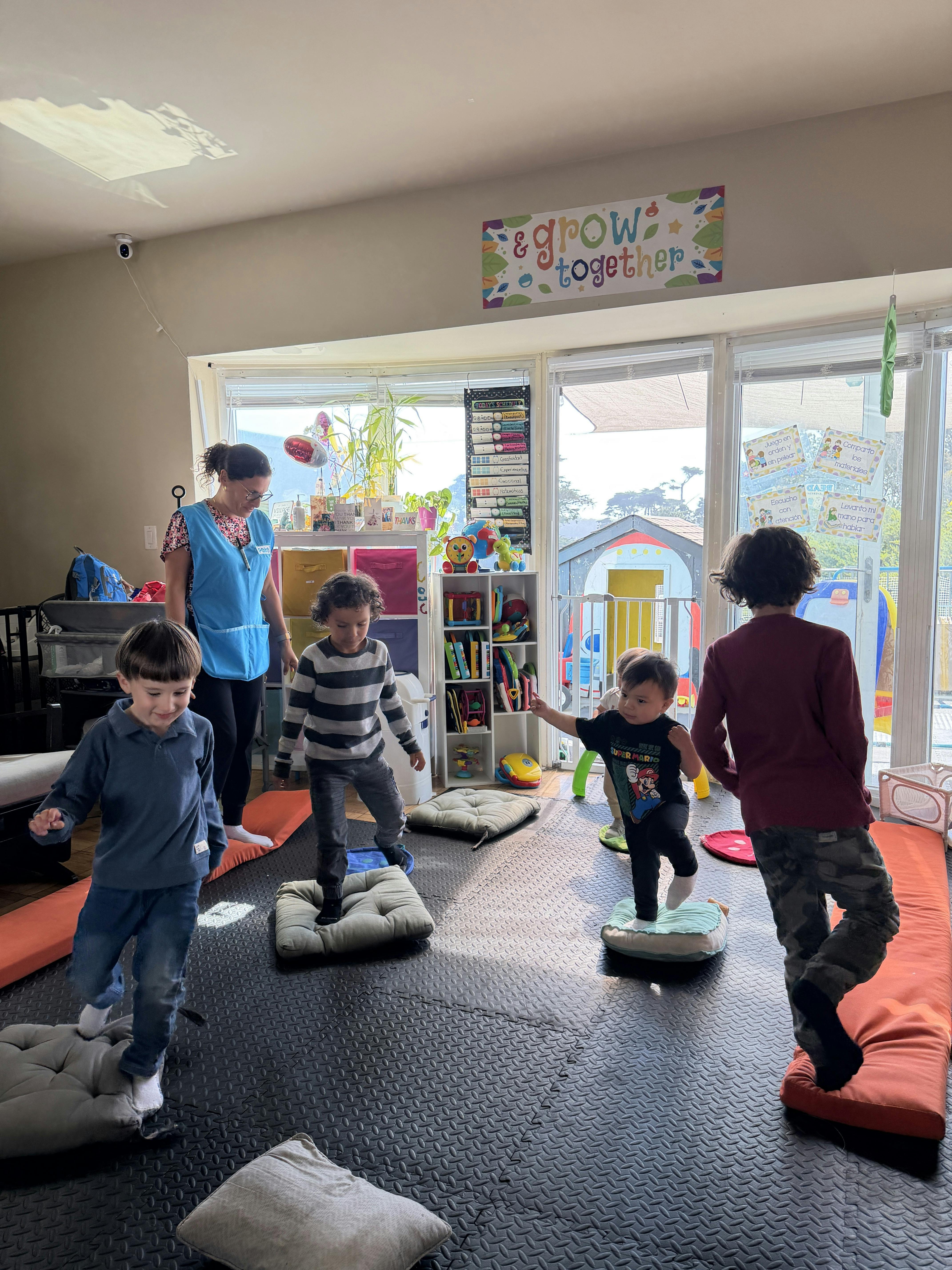 Group of children balancing on floor cushions in a daycare classroom