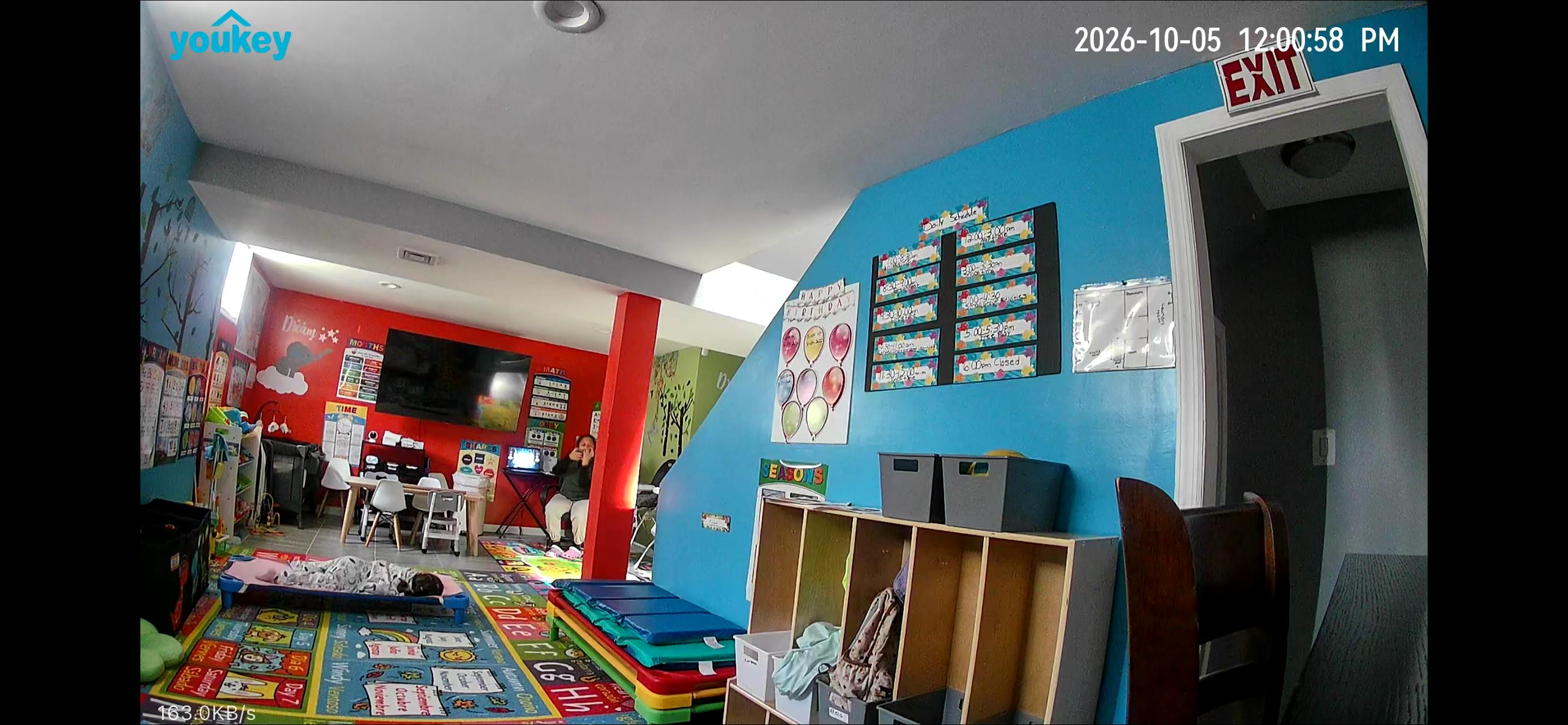 Child napping on a cot in a brightly colored preschool classroom