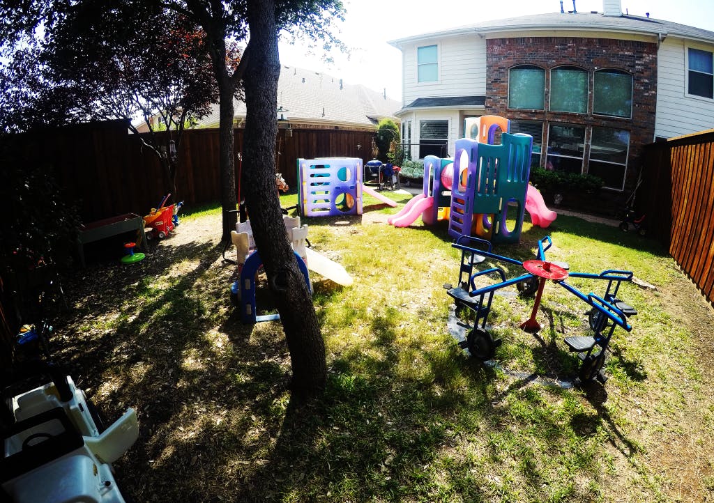 Backyard with play structures and a house in the background