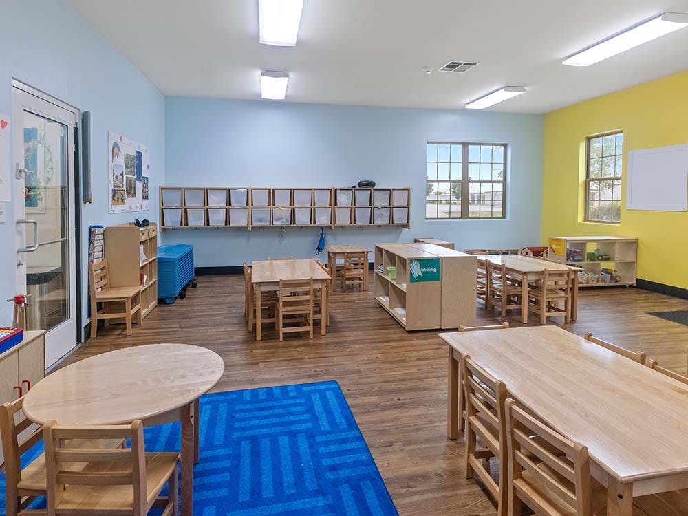 Empty classroom with small wooden tables and chairs on a wooden floor