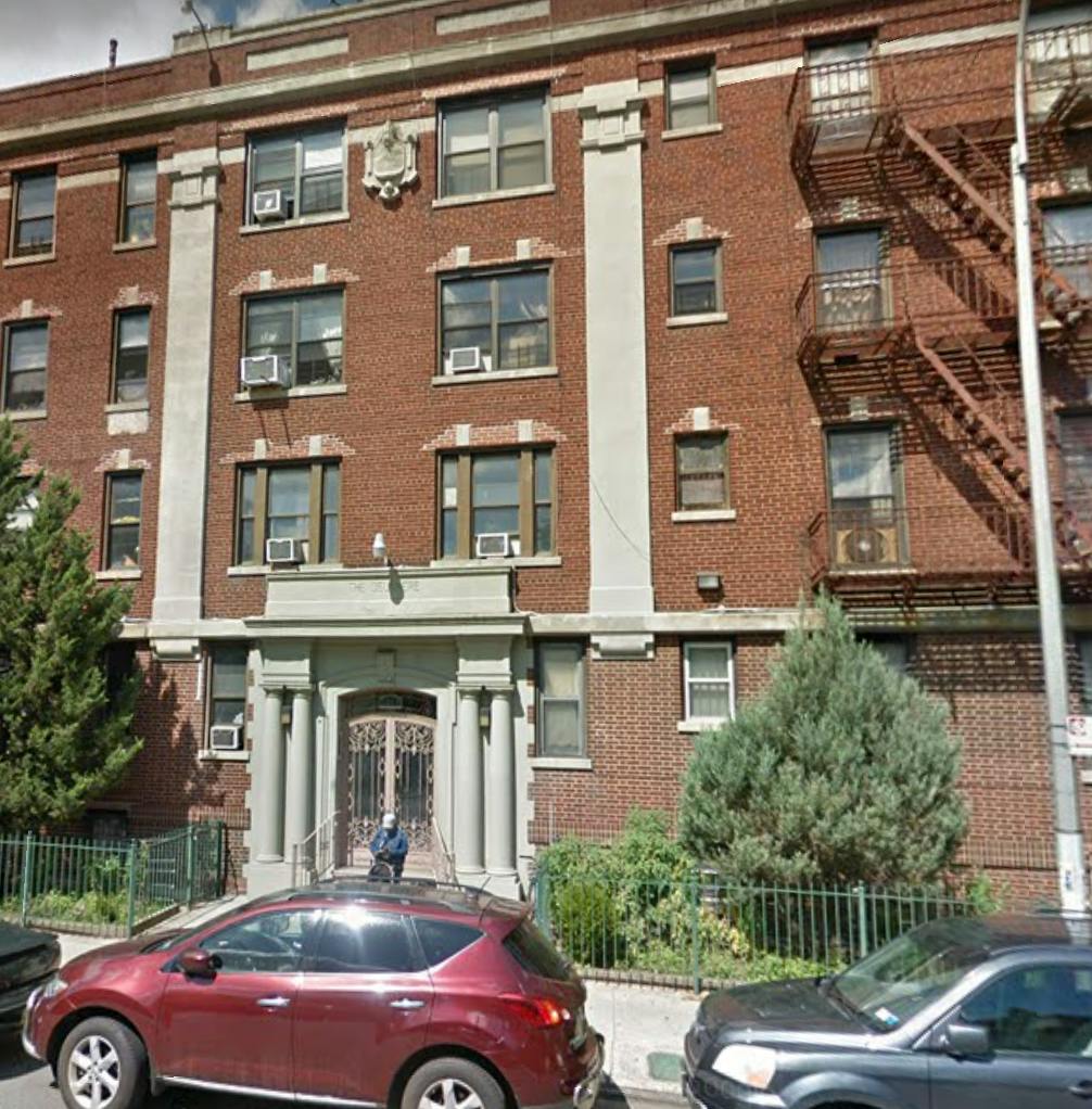 Brick apartment building with fire escape and parked cars
