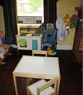 Child's play kitchen and small table with chairs in a room