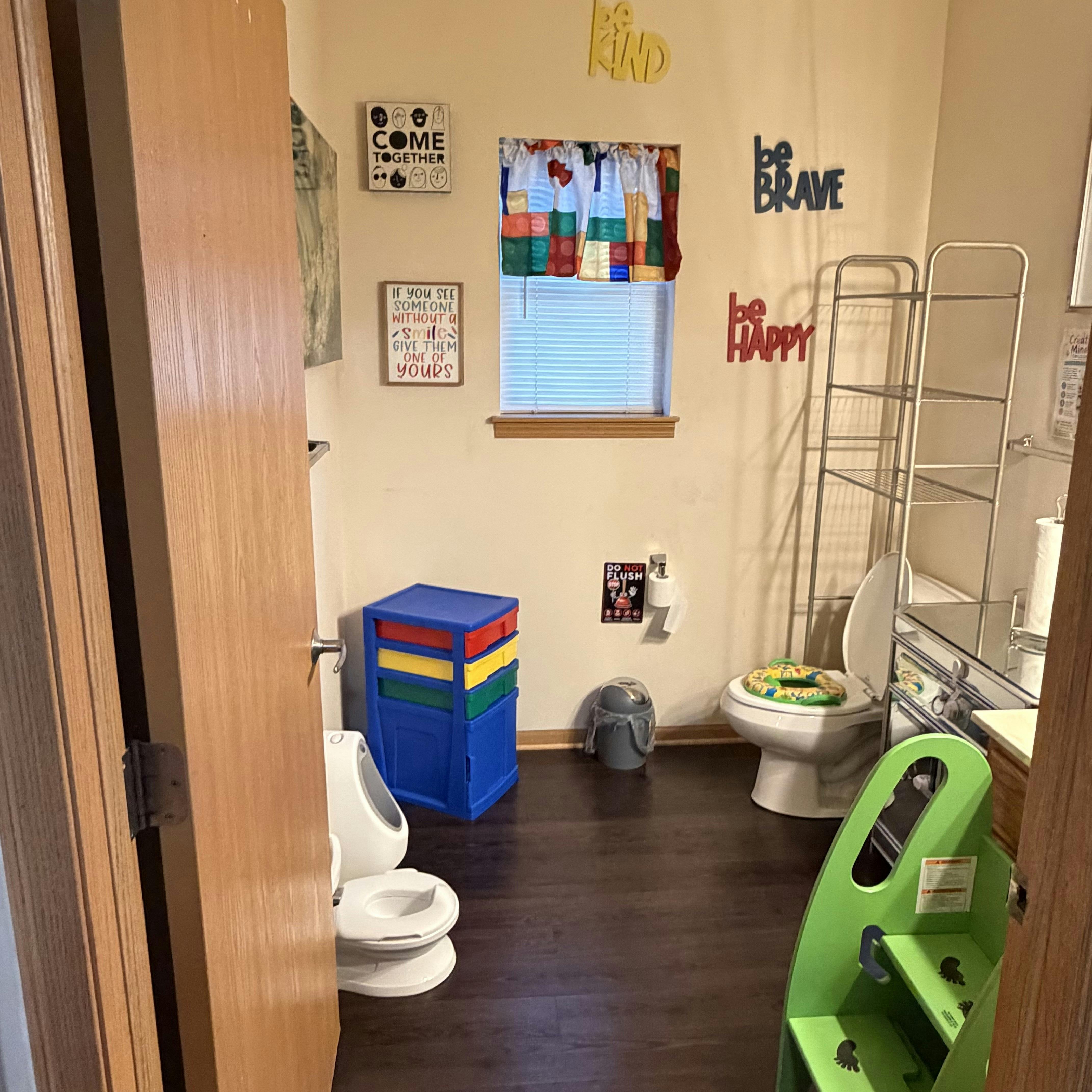 Child-sized bathroom with two toilets and a green step stool