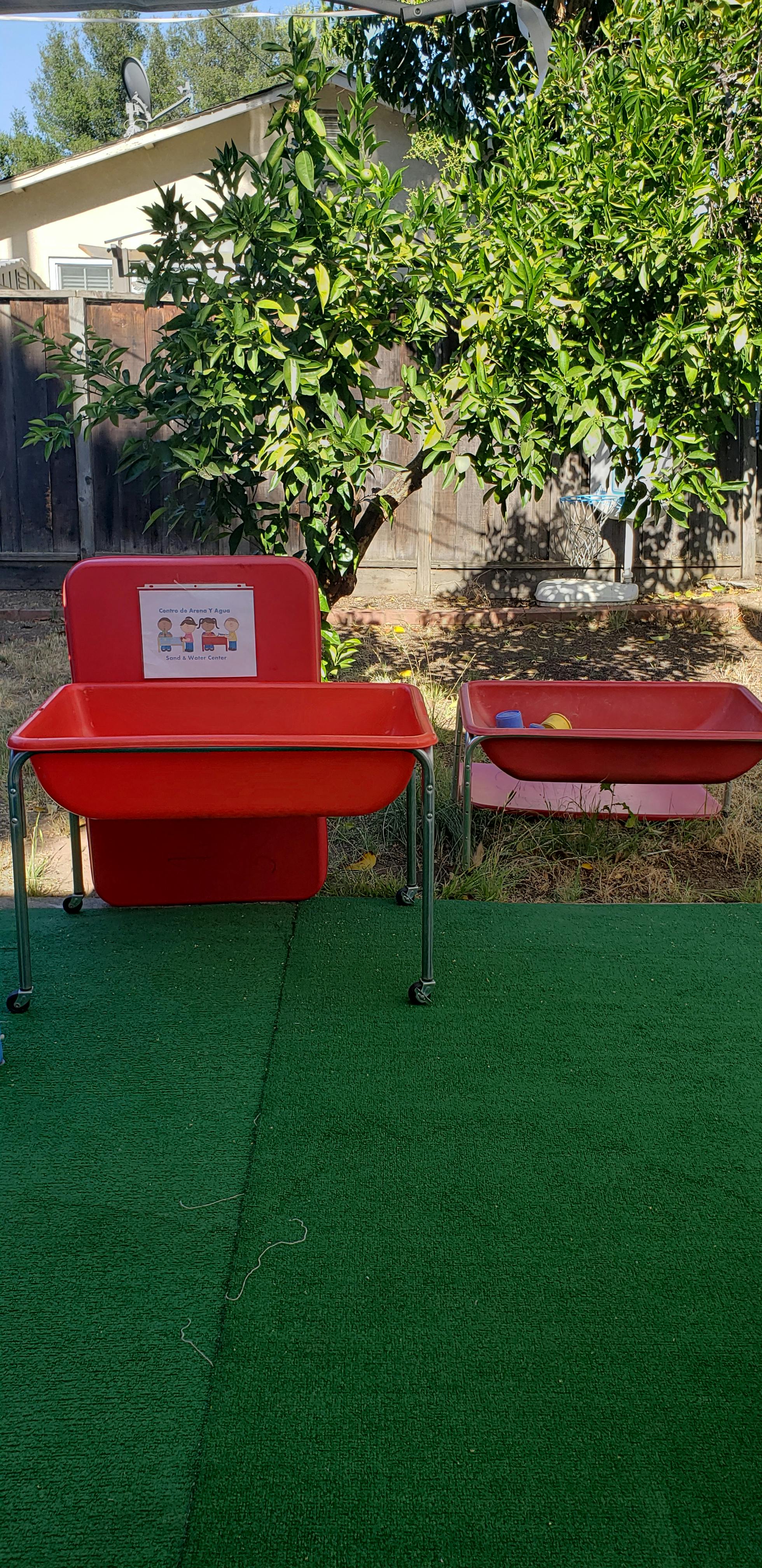 Two red sensory tables on green turf outdoors