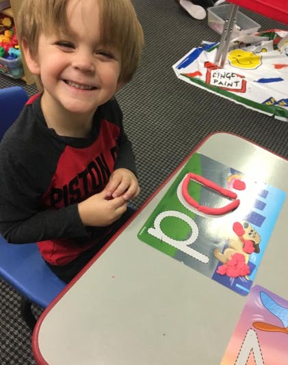 Child at a table with play-doh and letter cards
