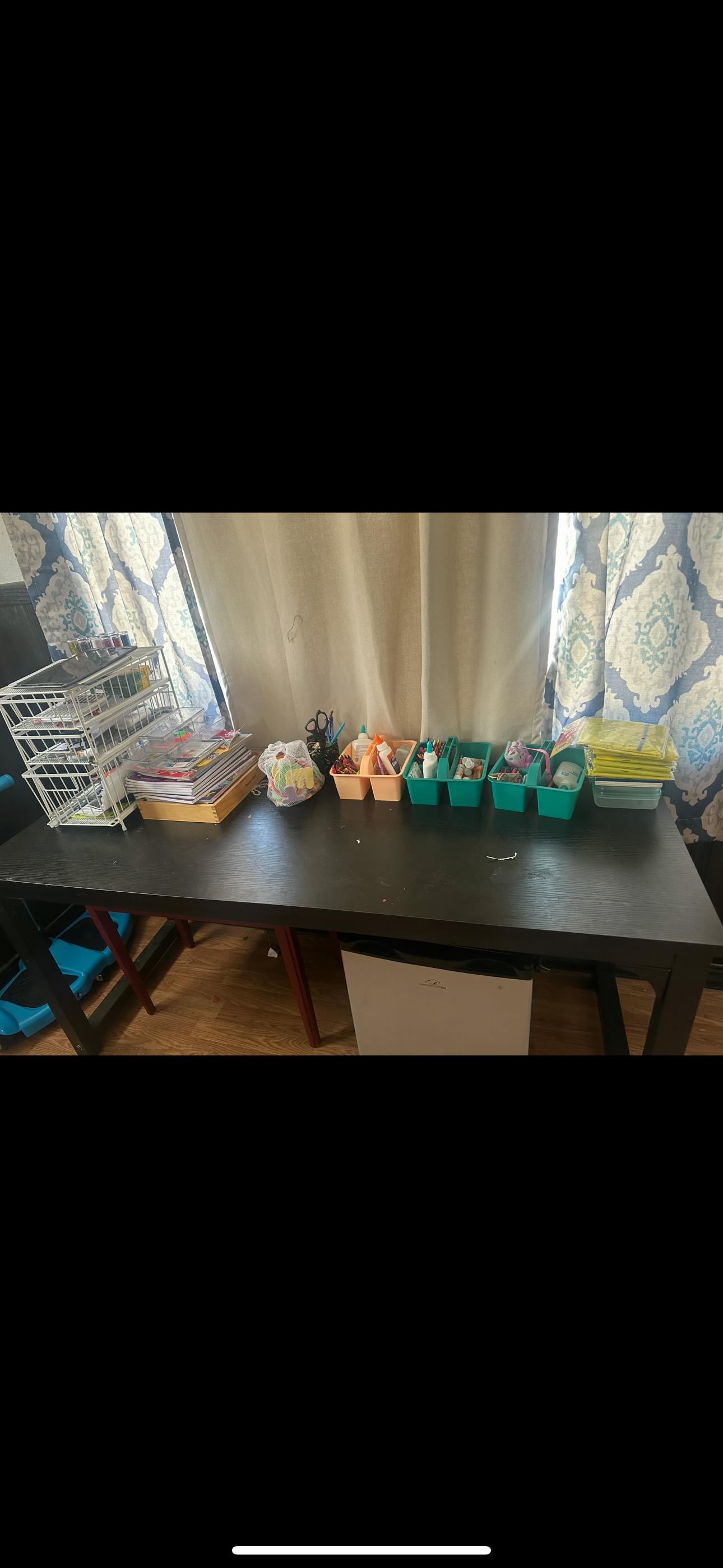 Table with a wire rack, stacked papers, and several caddies with supplies