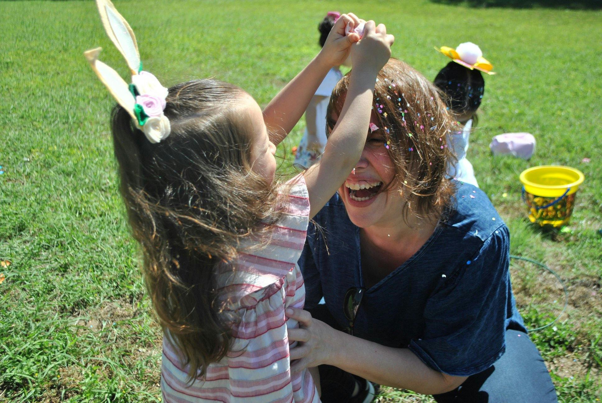 Child with bunny ears pouring confetti on a person's head