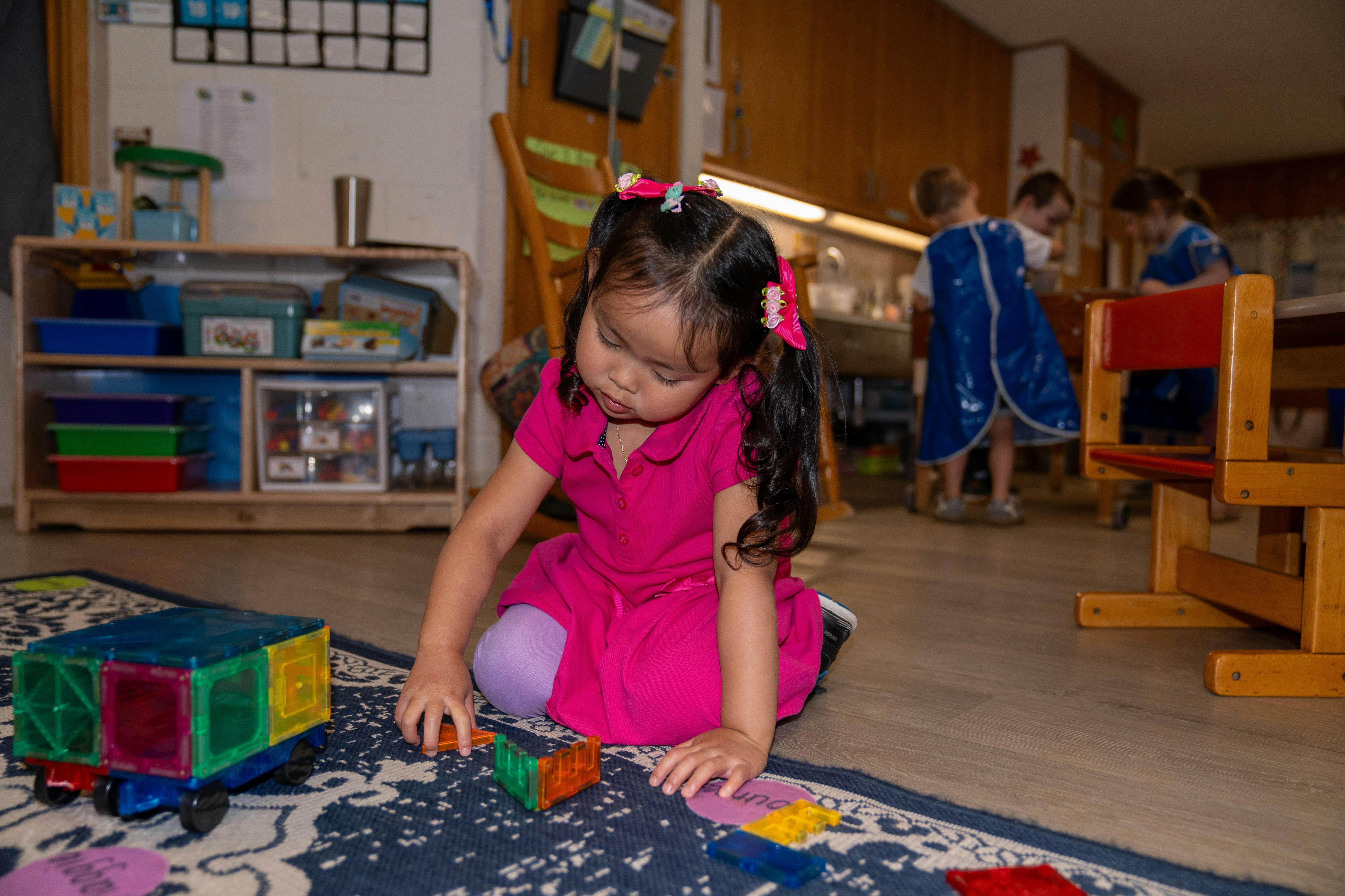 Child playing with colorful blocks on a rug in a classroom
