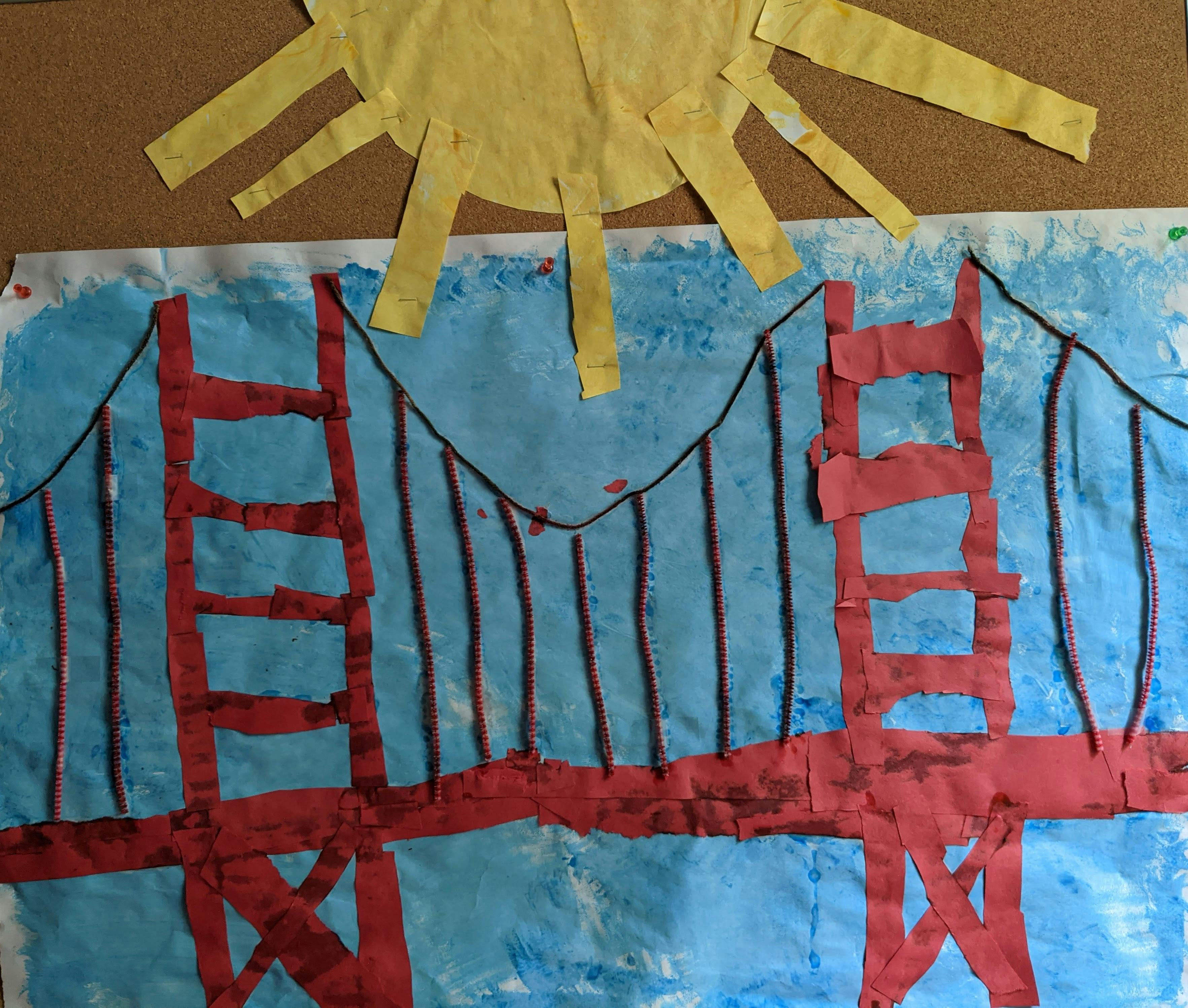 Child's drawing of a red bridge over blue water with a yellow sun