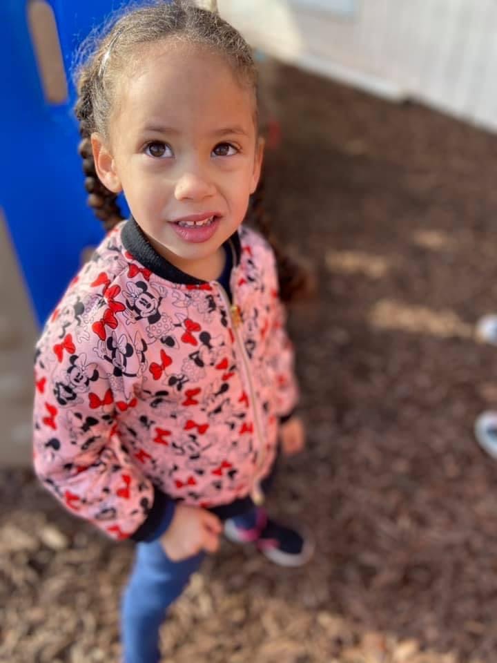 Child in a pink jacket with Minnie Mouse bows