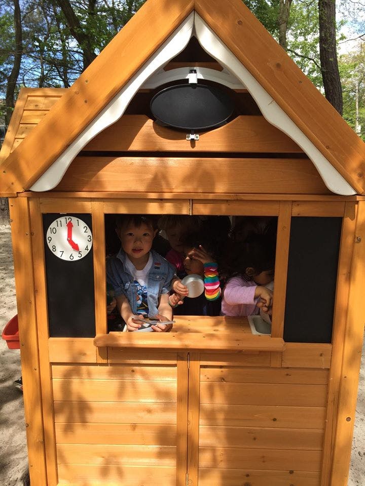 Child looking out of a wooden playhouse window