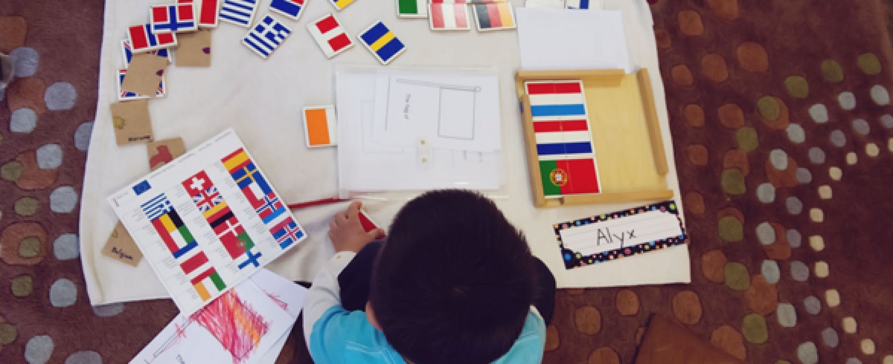 Child drawing at a table with flags