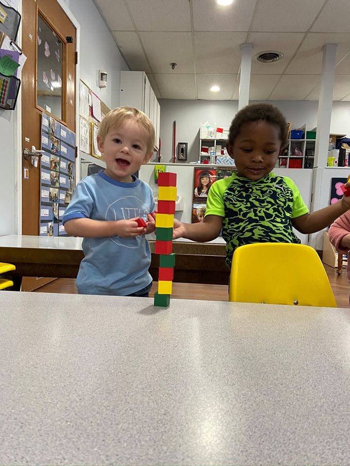 Two children playing with building blocks on a table