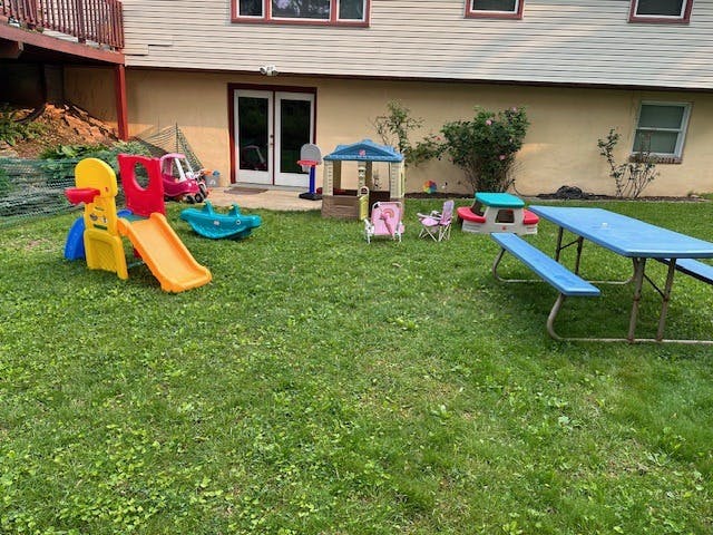 Plastic playground equipment and a picnic table in a backyard