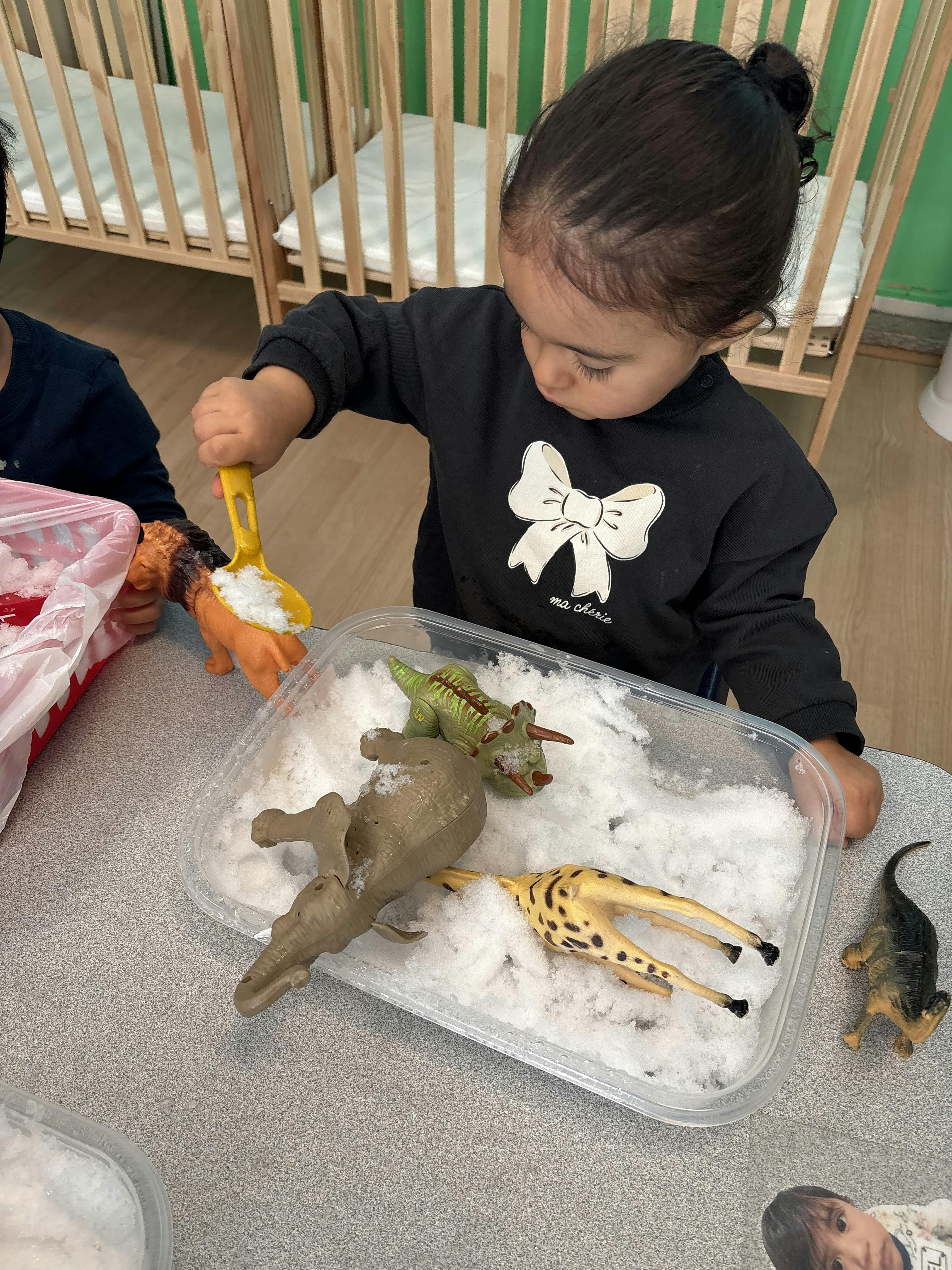 Child playing with toy animals and fake snow in a classroom