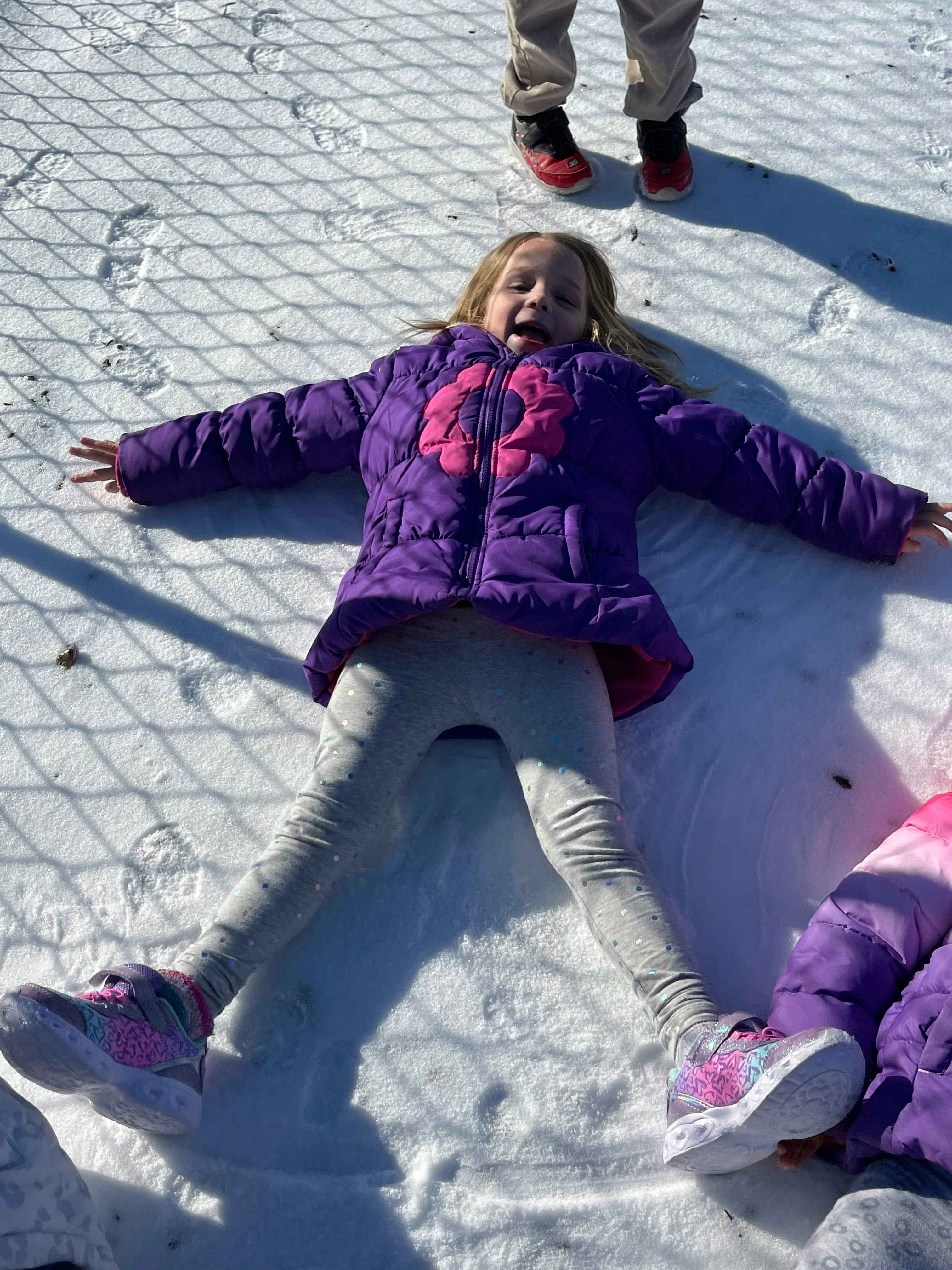 Child lying in snow with arms and legs spread