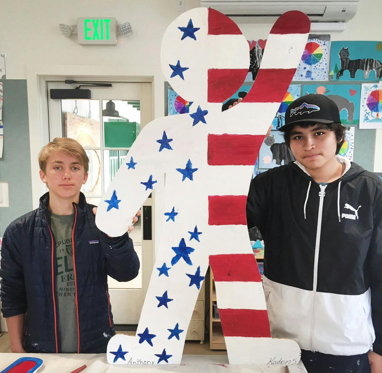 Two teens standing next to a cutout of a person painted with stars and stripes