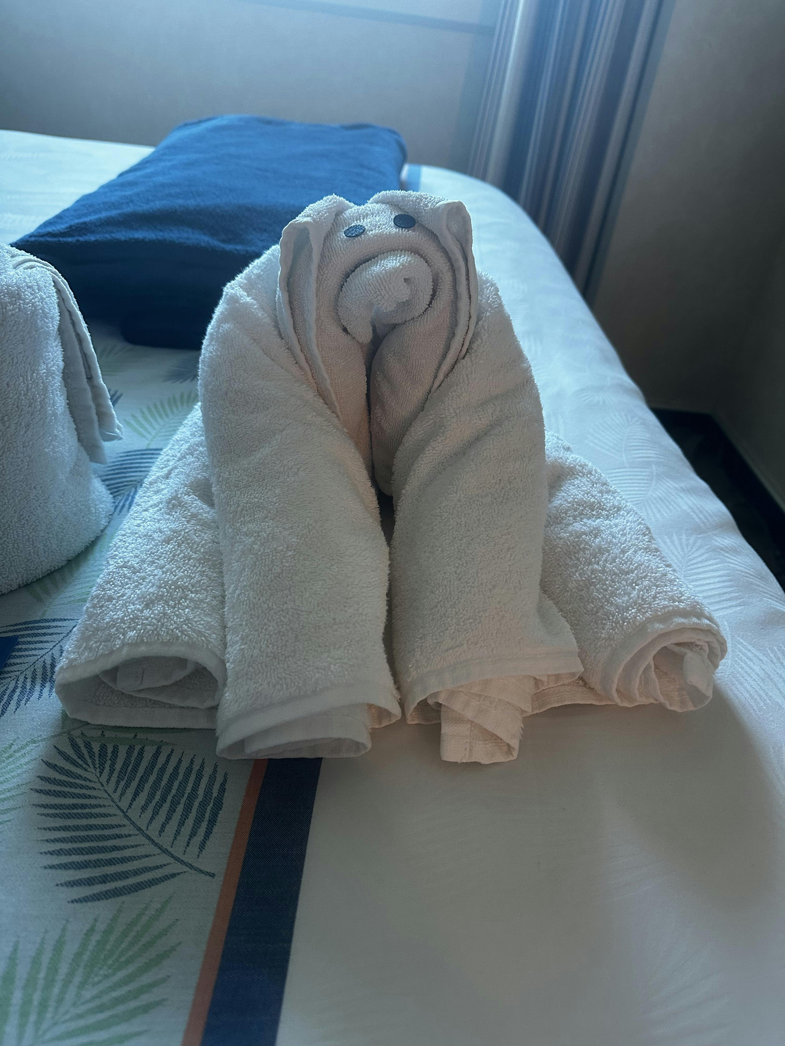 White towel folded into an animal shape on a bed