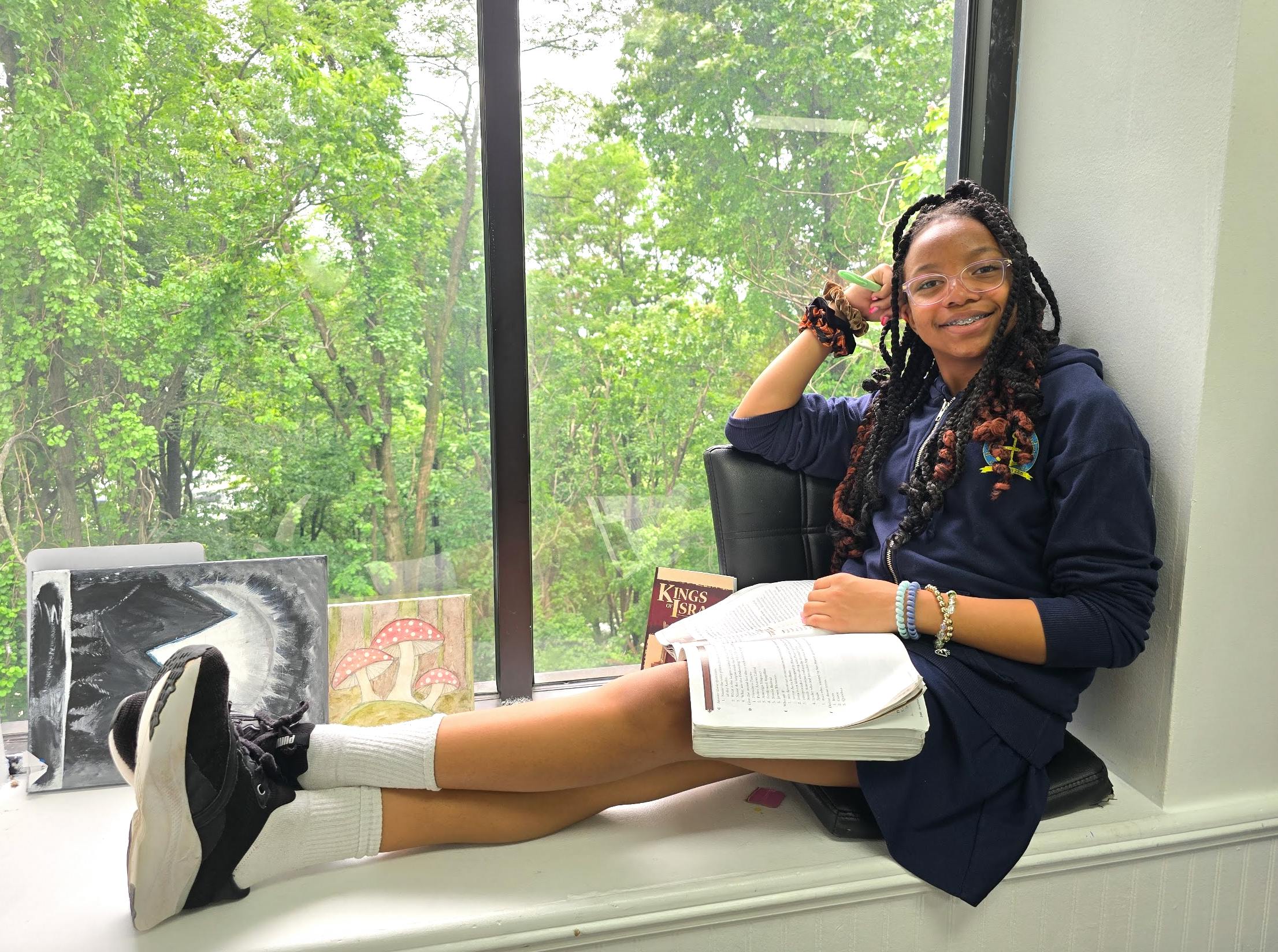 Teen sitting on a window ledge with a book