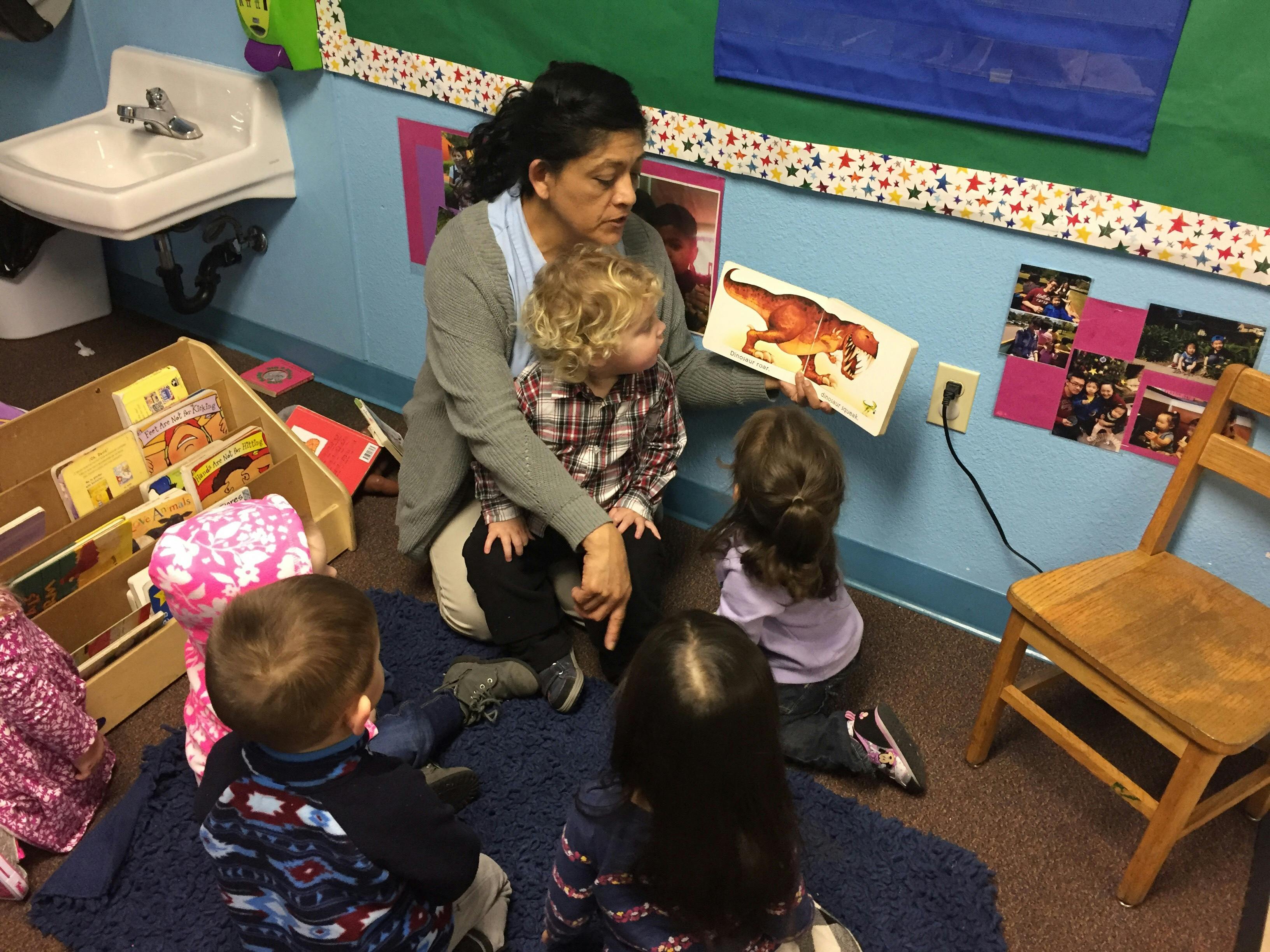 Person reading a book to children in a classroom