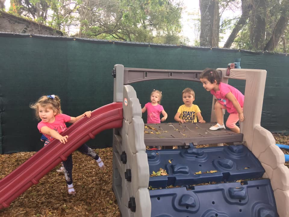 Children playing on a playground slide and climbing structure