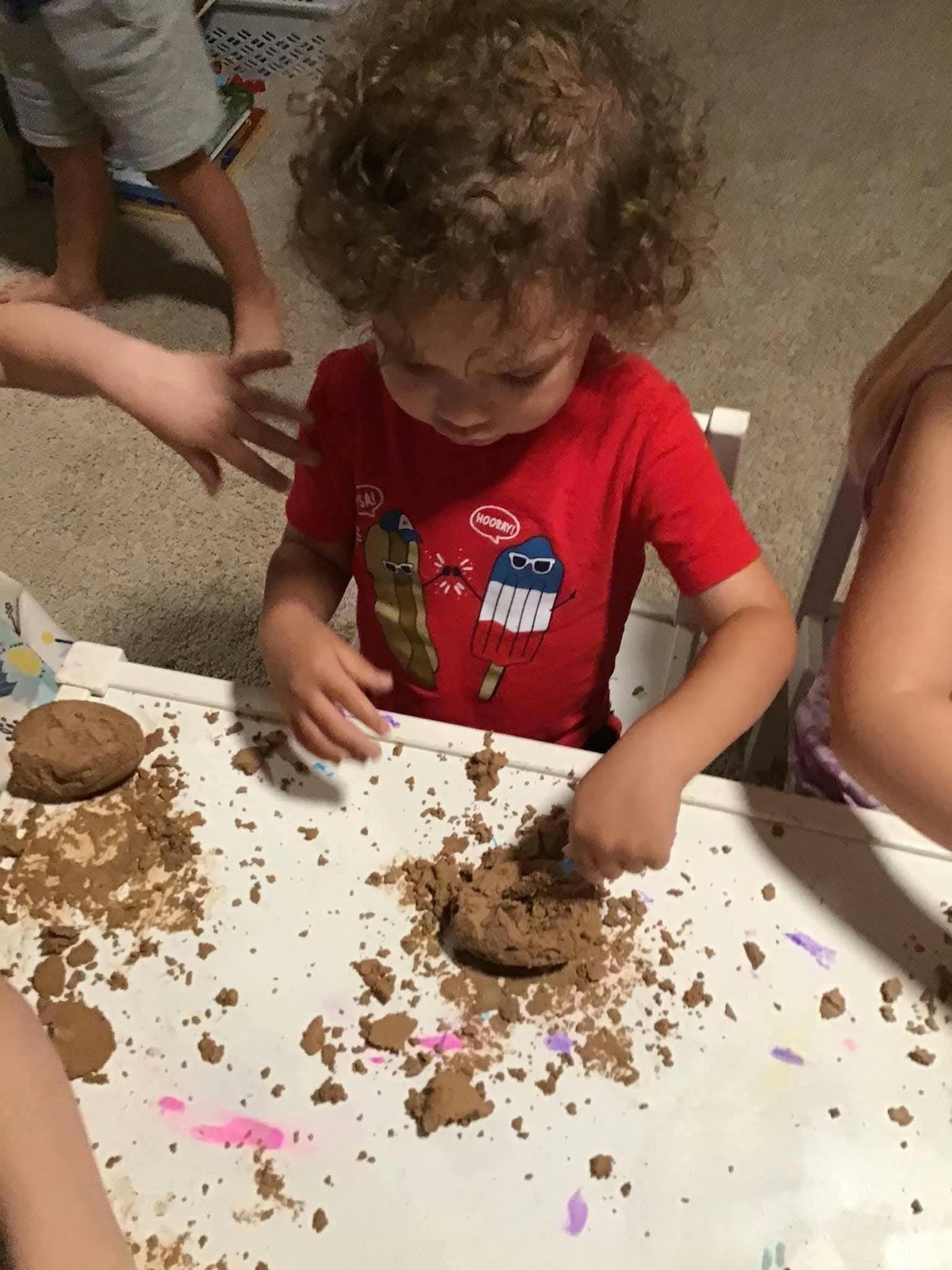 Child playing with kinetic sand on a white surface