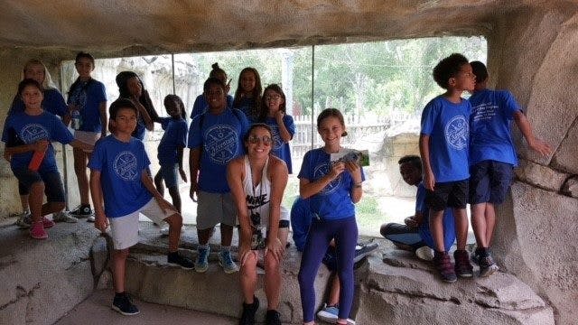 Group of children and adults in blue shirts standing in a cave-like structure