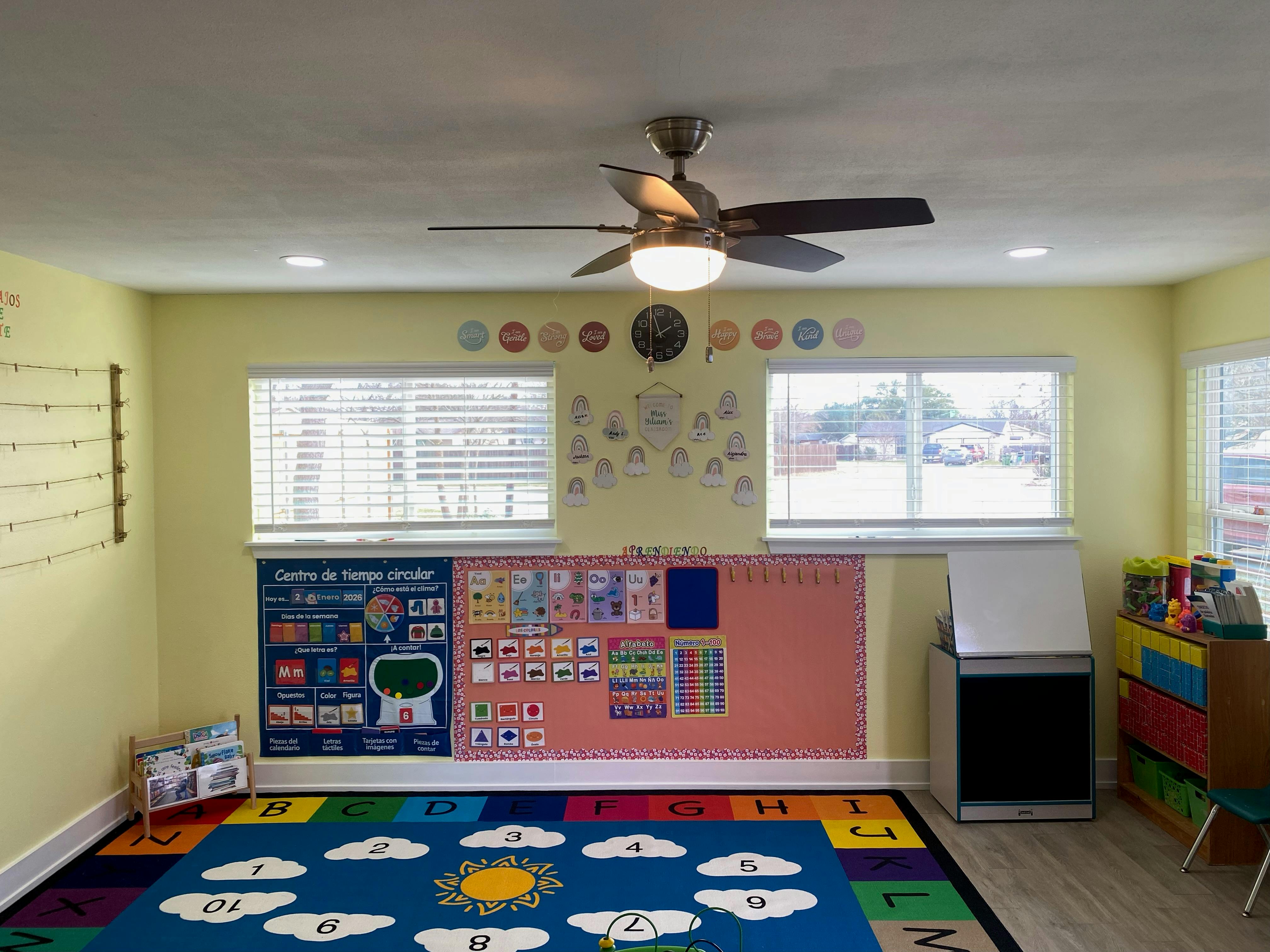 A classroom with a Spanish alphabet chart, calendar, and colorful rug with numbers