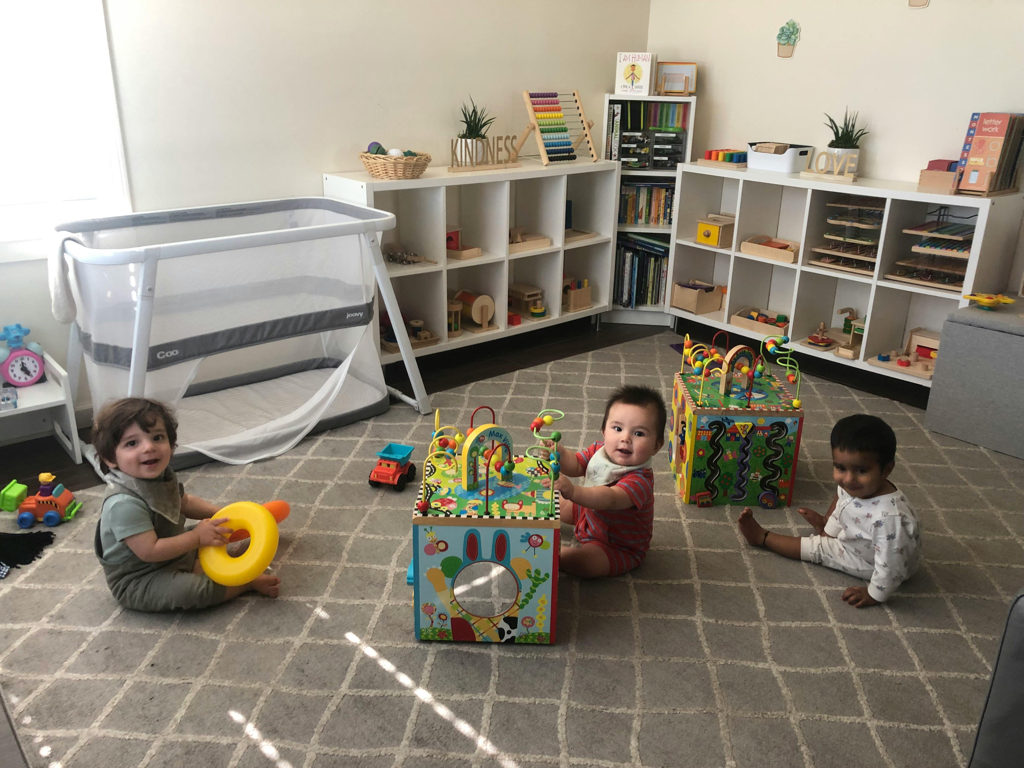 Three children playing with toys on a rug in a room