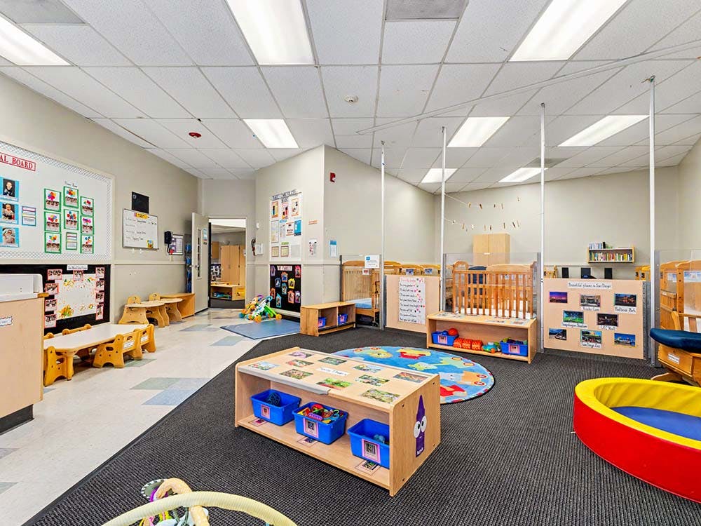 Empty colorful daycare or preschool classroom with cribs and play areas