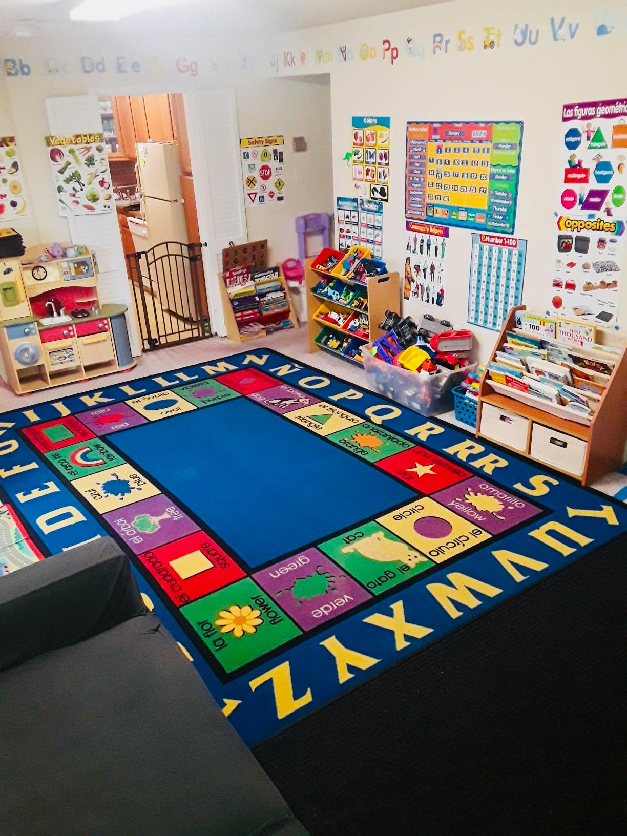 Child's play area with an alphabet rug, toy kitchen, and educational posters