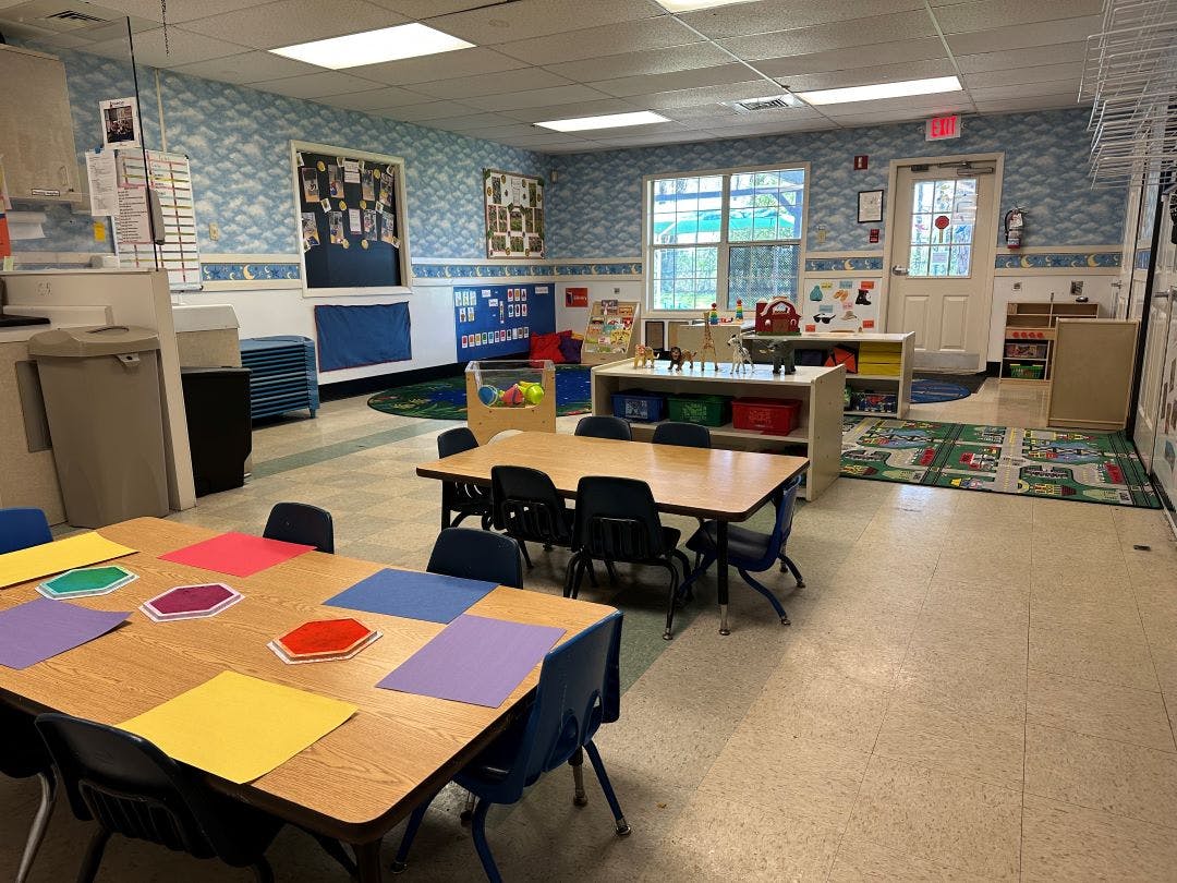 Empty colorful children's classroom with tables, chairs, and toys