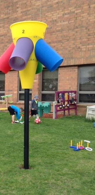 Children playing with a colorful outdoor toy and a red ball