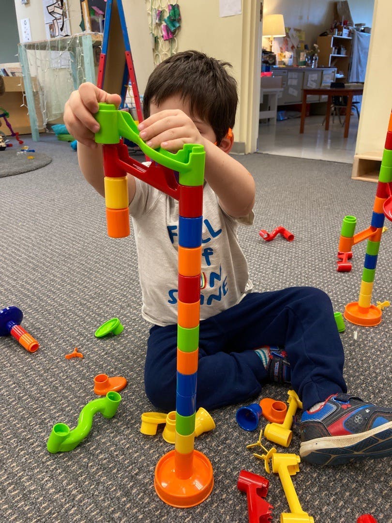 Child playing with colorful building blocks on the floor