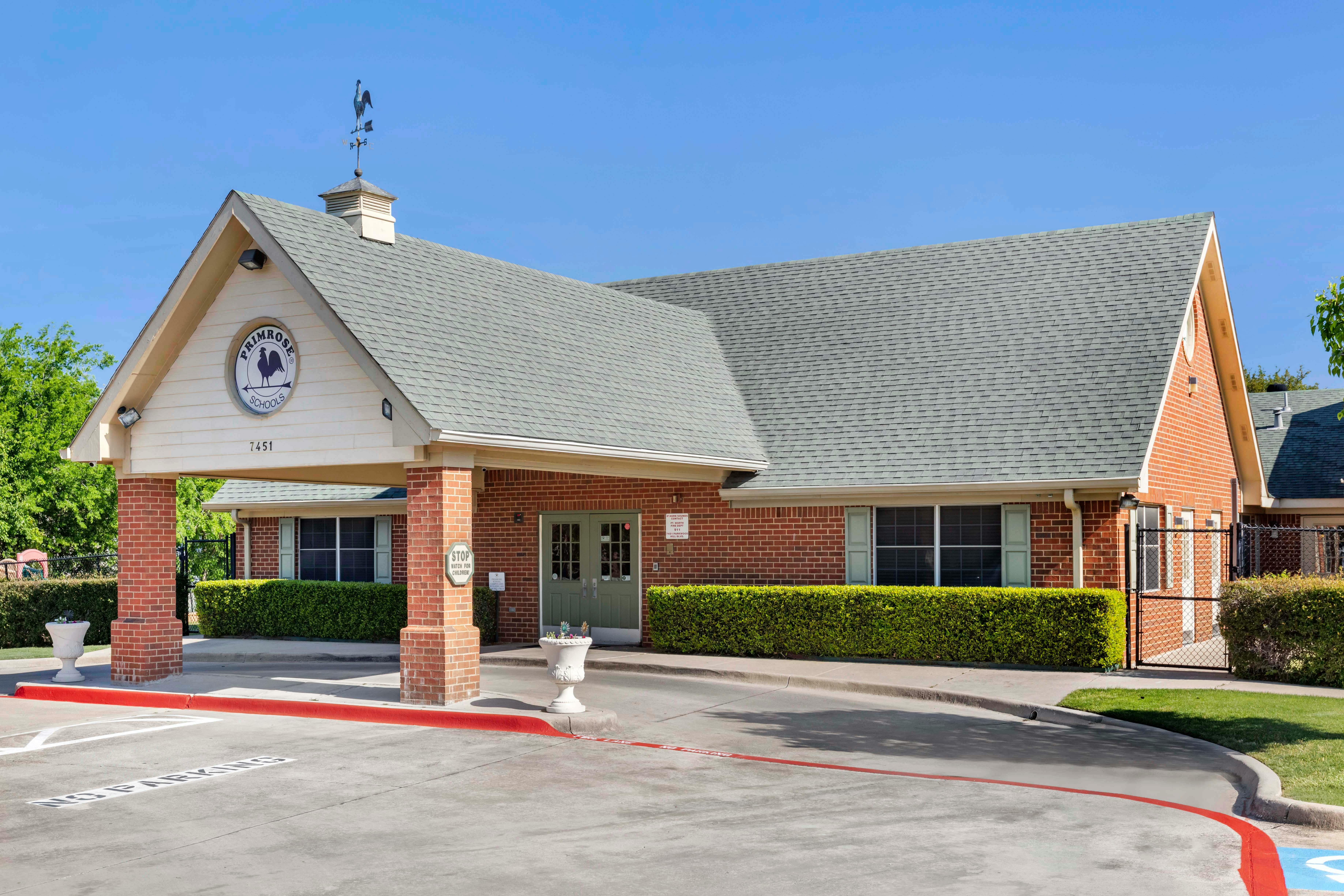 Brick building with a gray roof and a sign for Primrose Schools