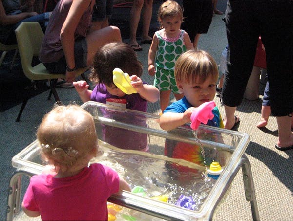 Children playing with water and toys in a clear bin