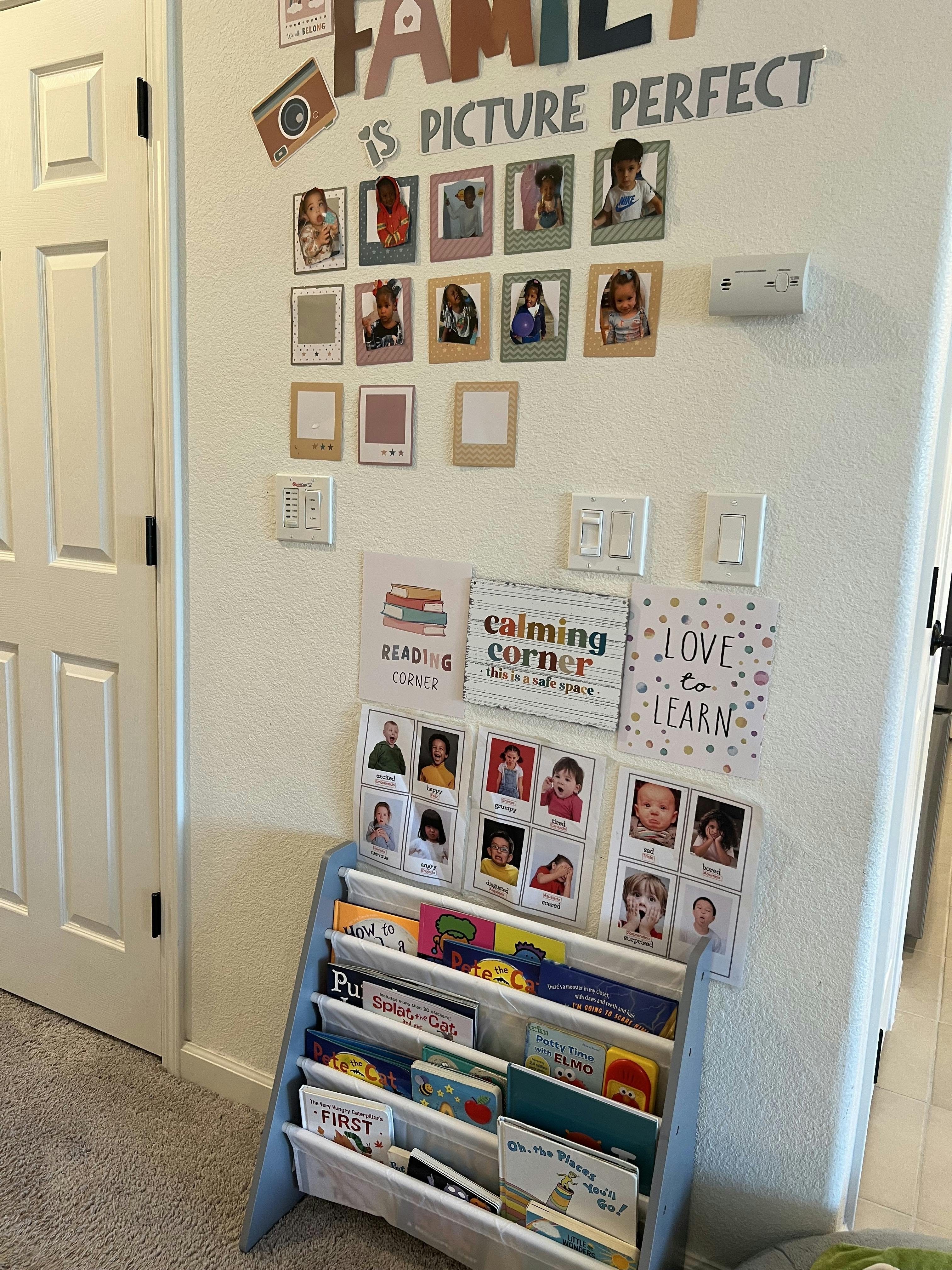 Wall with framed photos, text, and a small bookshelf filled with books