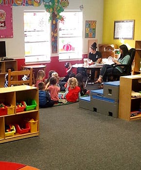 Two people with a group of children in a classroom