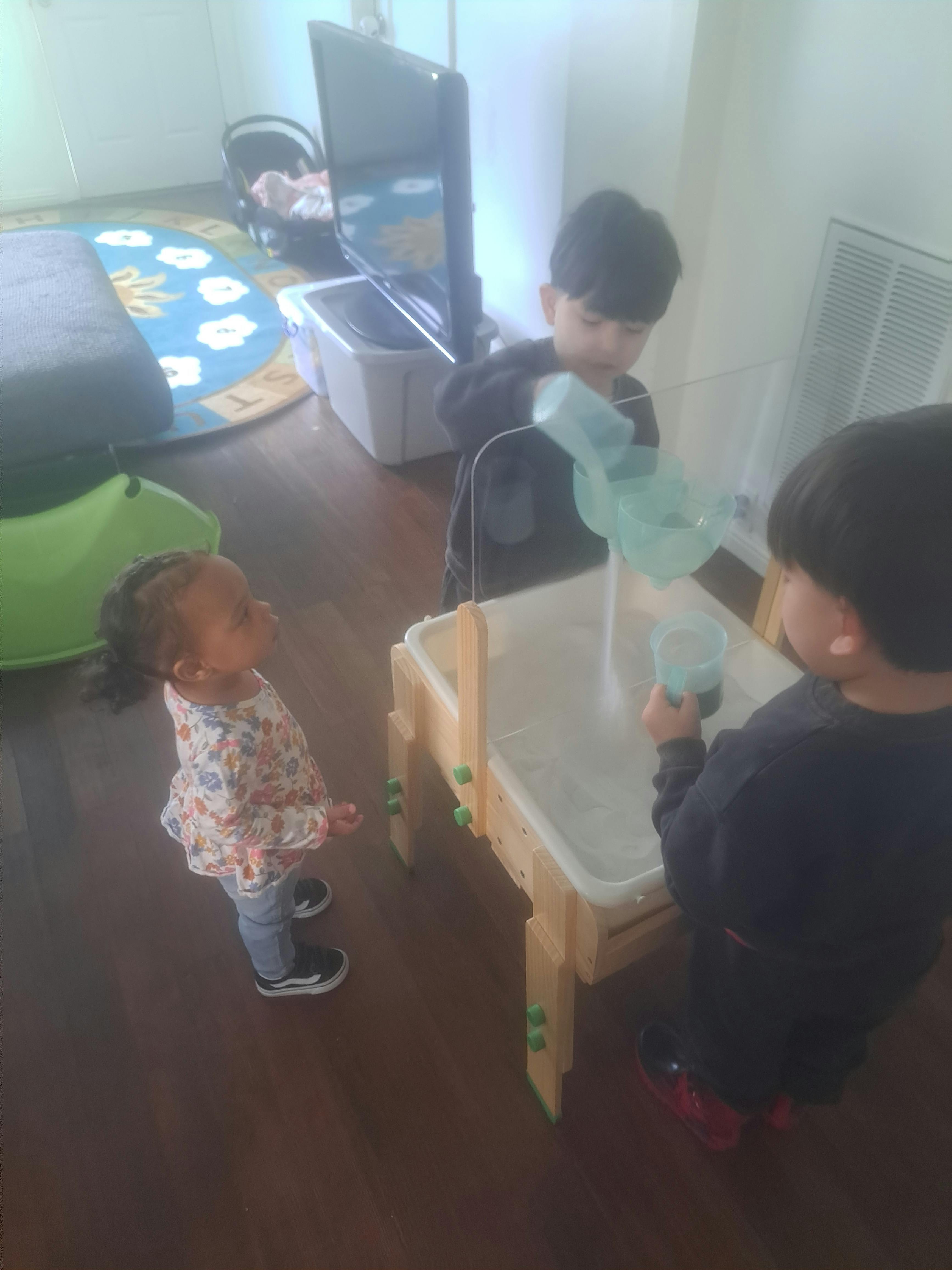 Three children playing with water at a sensory table