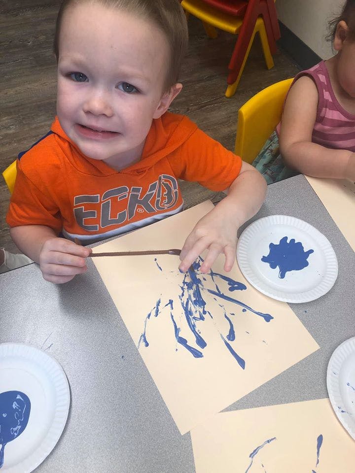 Child painting with blue paint on paper