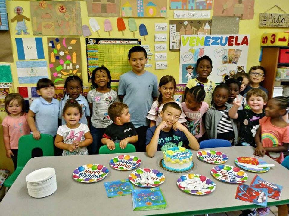 Group of children and teens around a table with a birthday cake