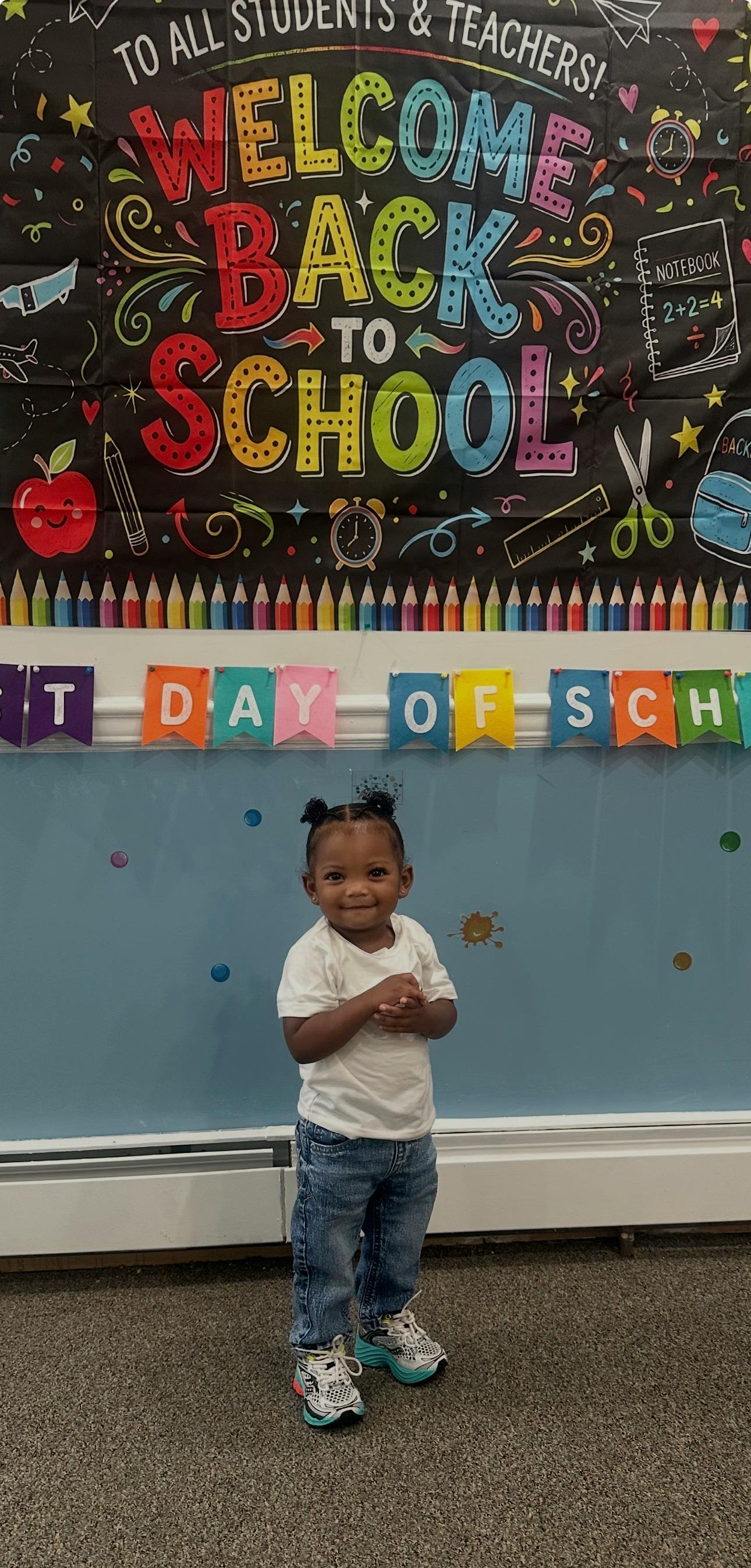 Child standing in front of a Welcome Back to School banner