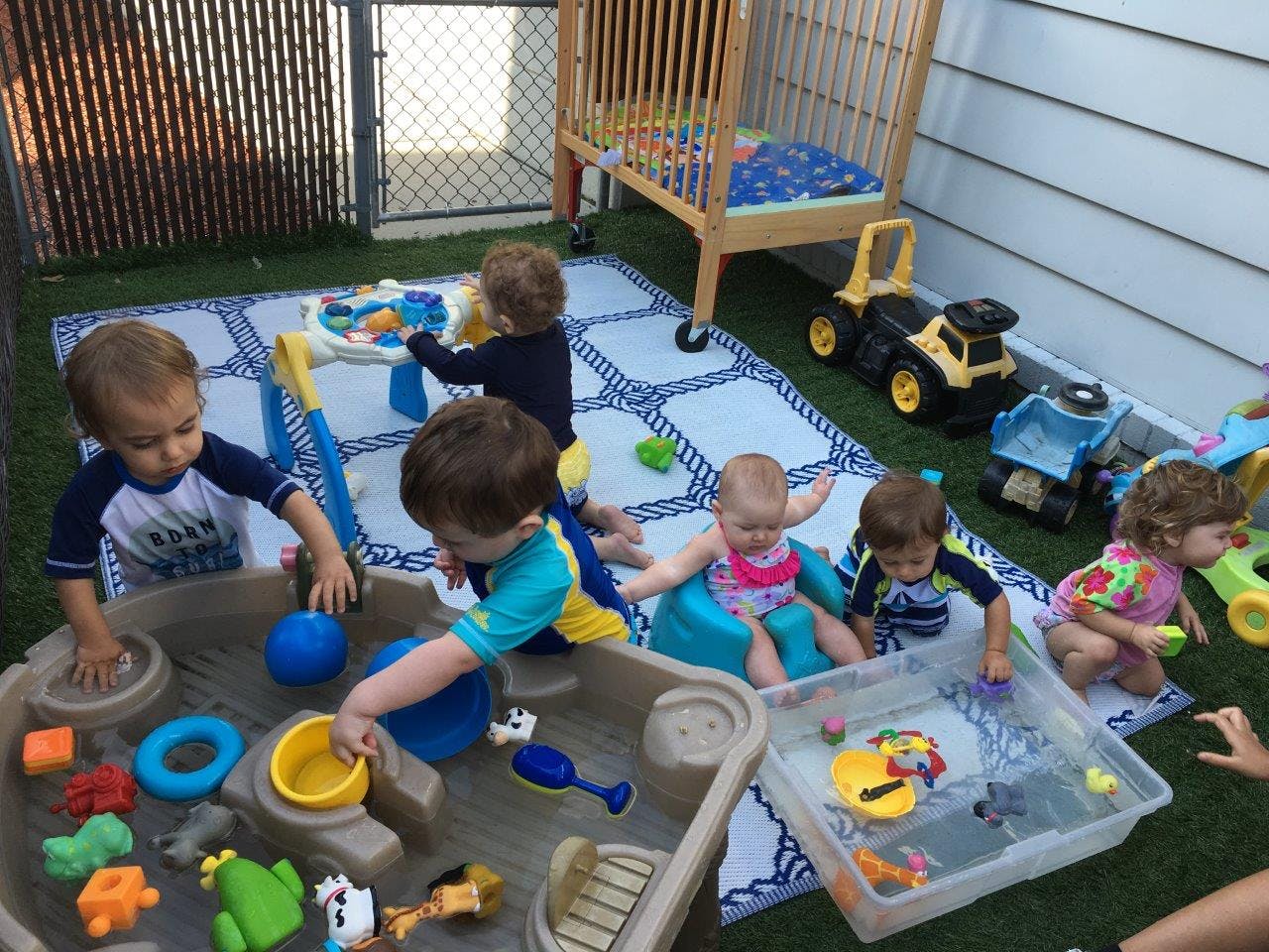 Multiple children playing with water and toys in an outdoor play area