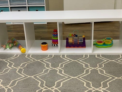 White shelf with various toys on a patterned rug