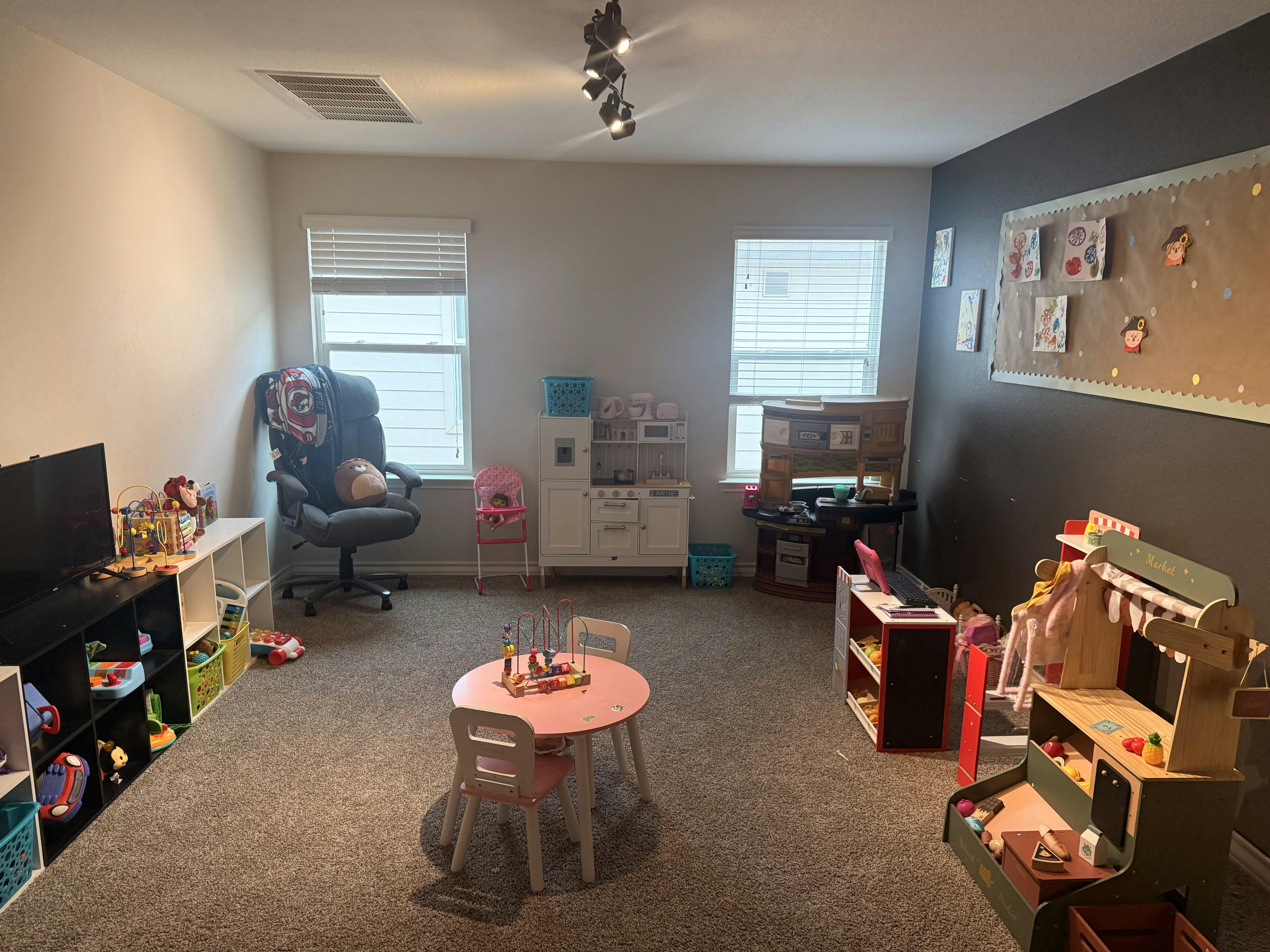 Playroom with a round table, toy kitchen, and various toys