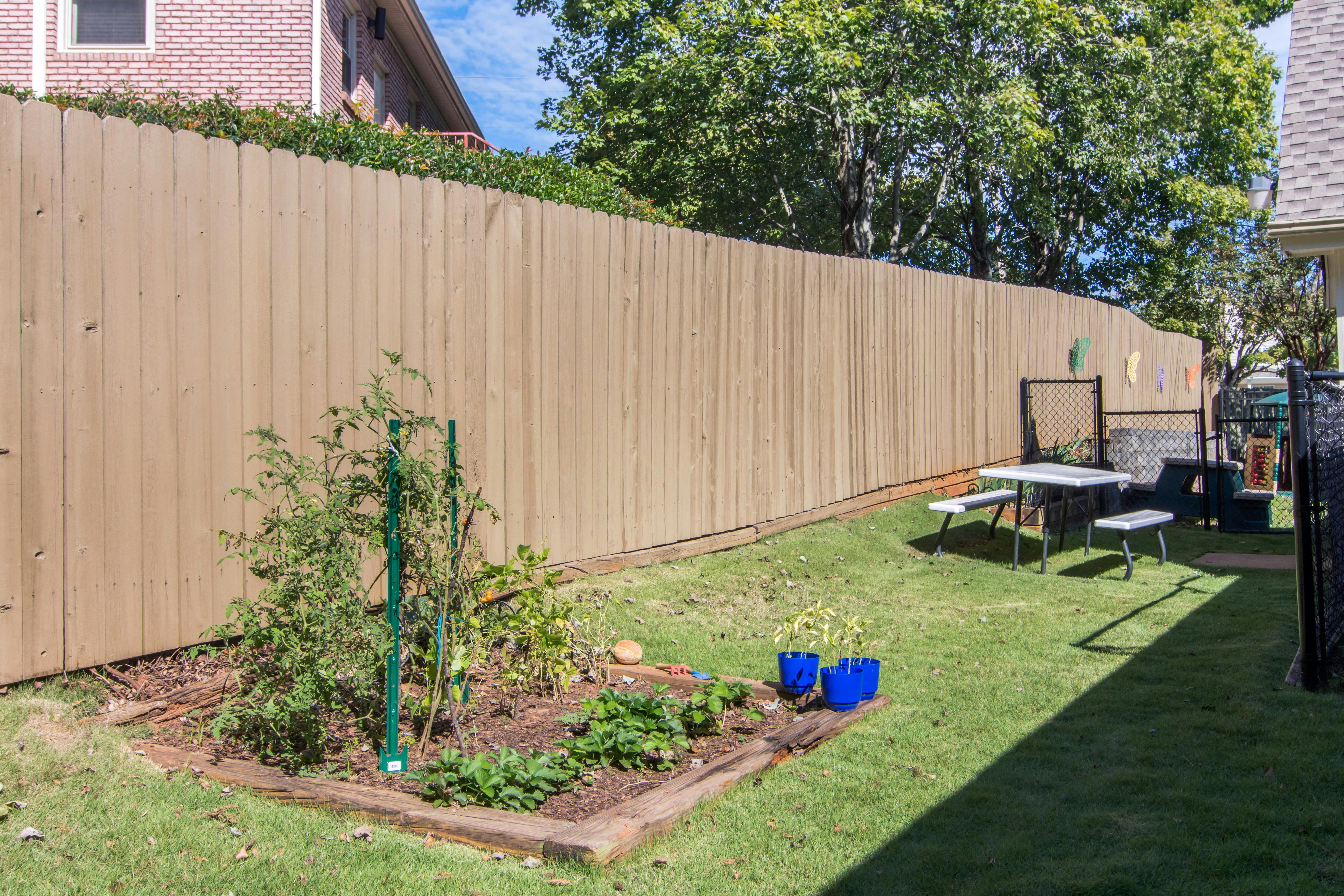 backyard garden with a wooden fence and a picnic table