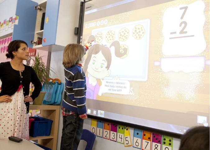 Person and child looking at an interactive screen in a classroom