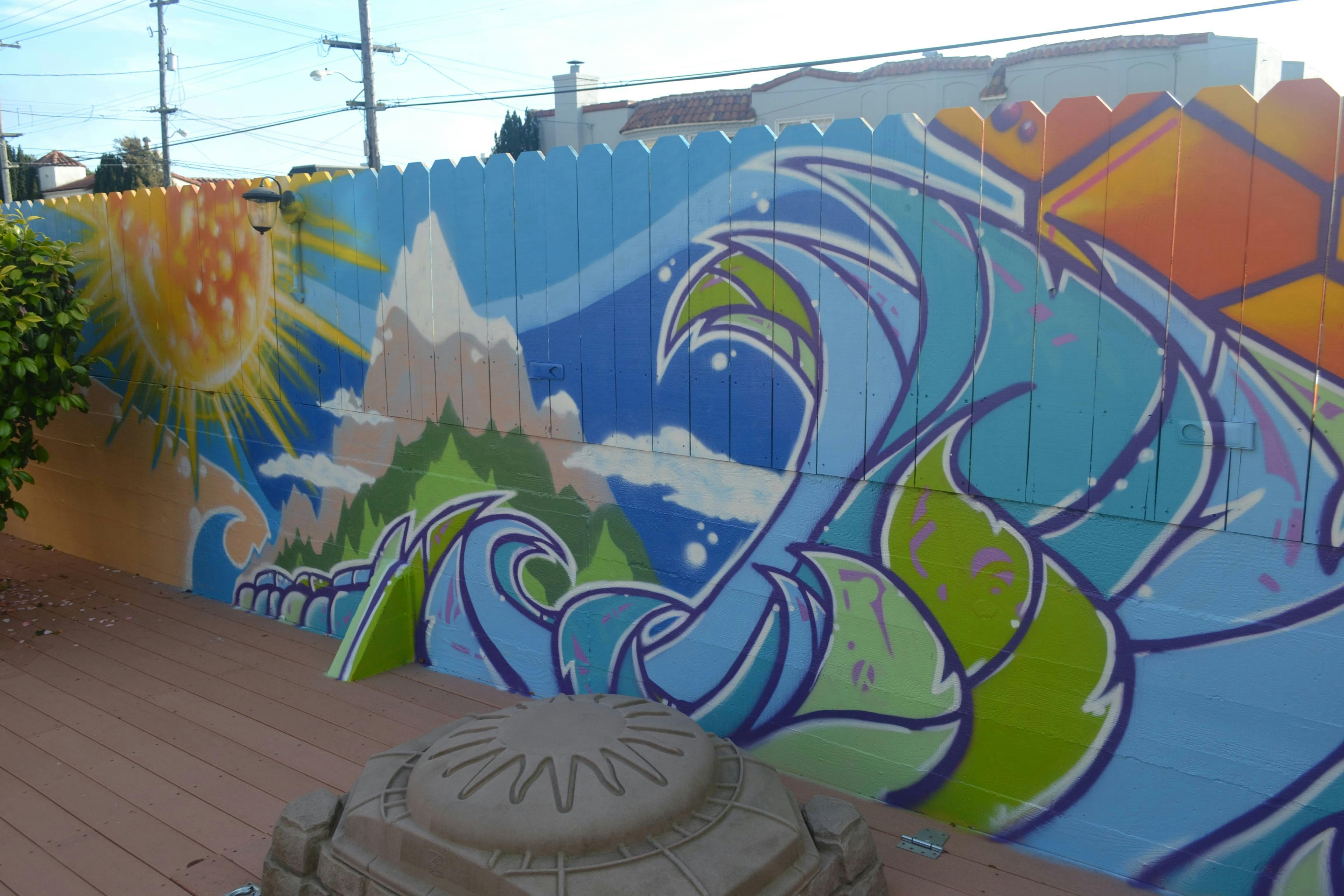 Fence mural with sun, mountains, and waves
